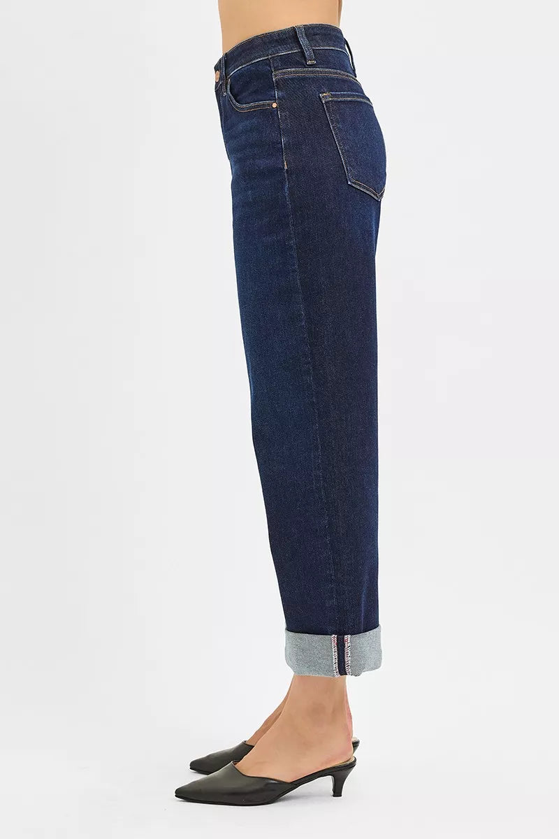 Dark mid-rise wide-leg jeans from side view, rolled ankle hem