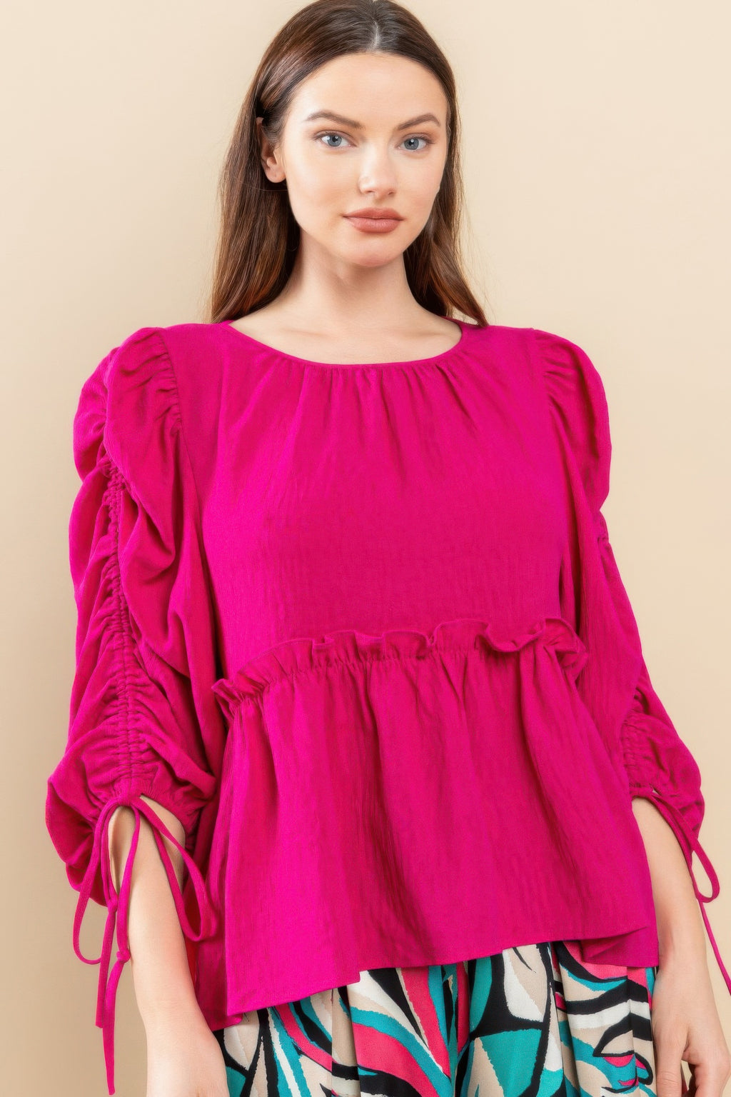 Magenta babydoll top with round neckline, gathered waist and puff sleeves, tie cuffs