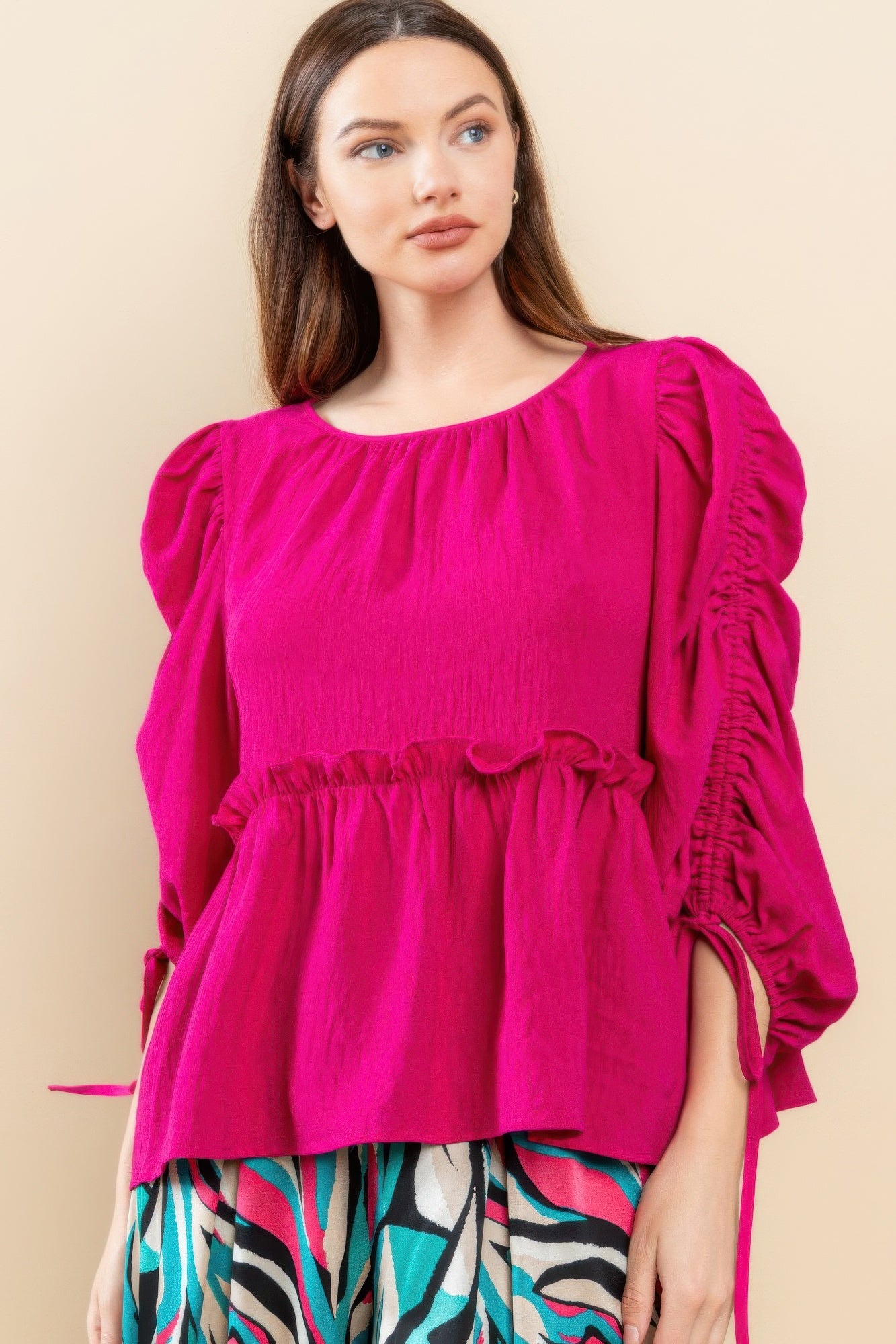 Magenta babydoll top with round neckline, pleated yoke, and tie-detailed puff sleeves