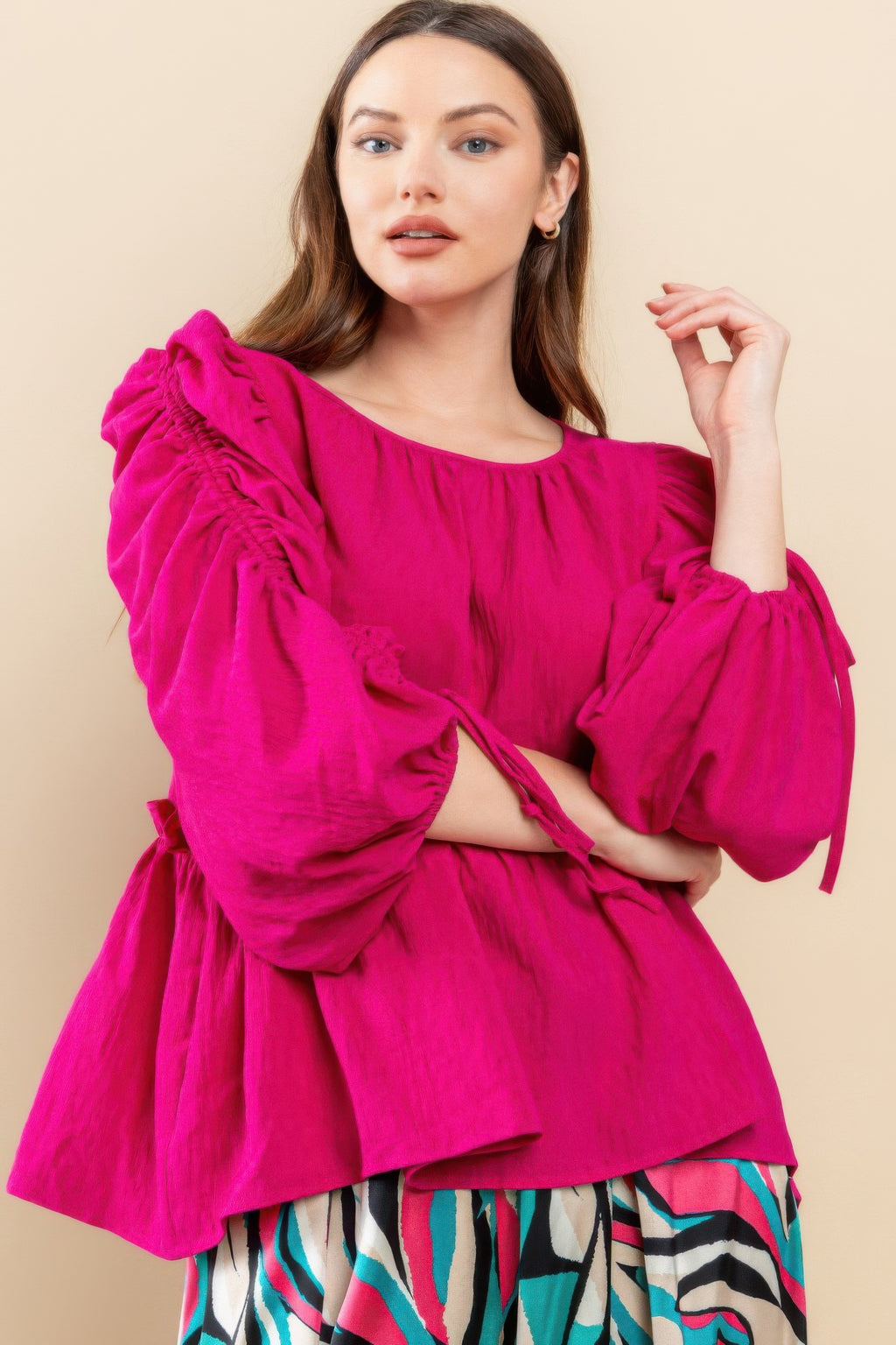 Magenta babydoll top with ruched puff sleeves, drawstring tie cuffs, and tiered skirt hem