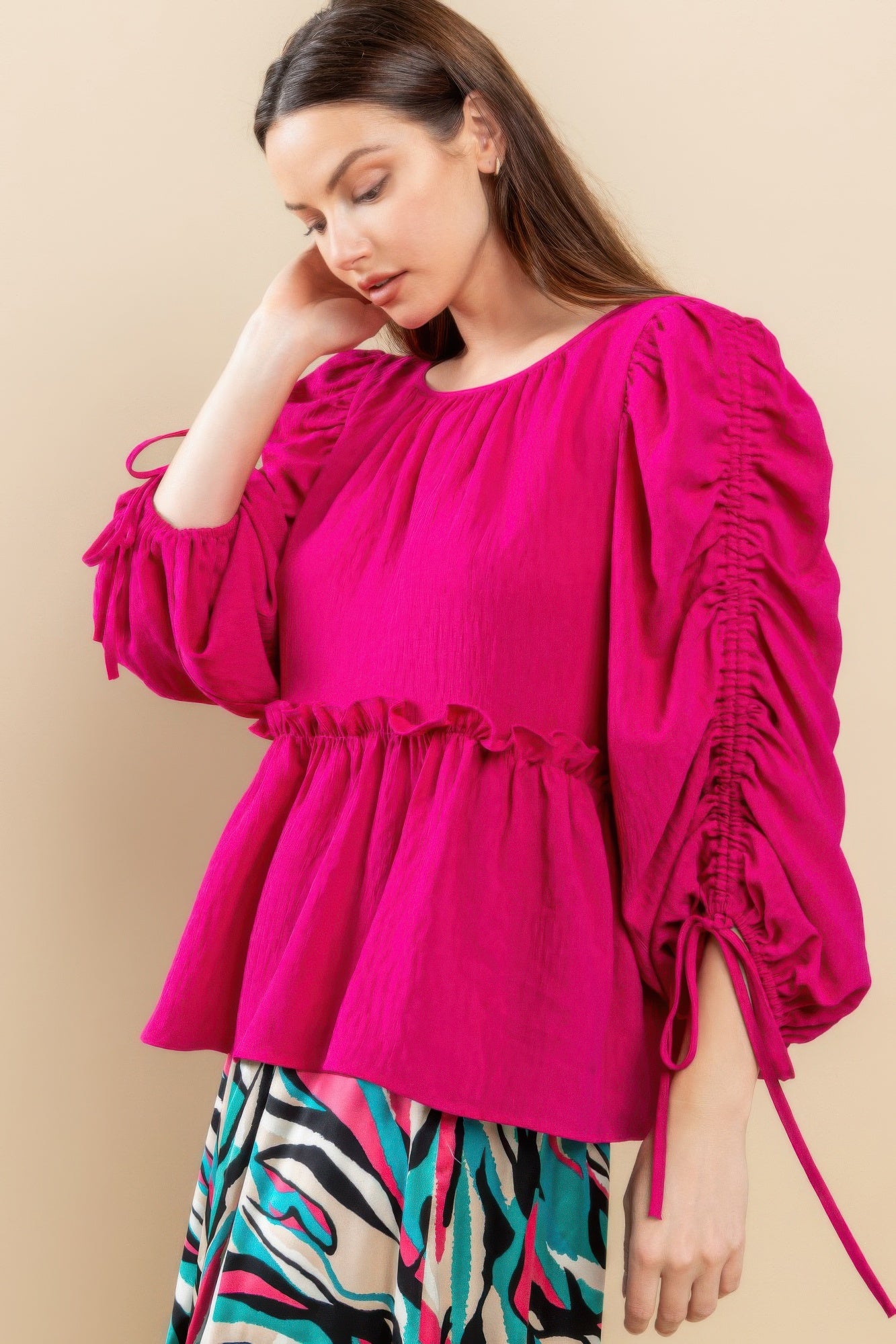 Magenta babydoll top with round neckline and gathered waist; tie cuff details on sleeves