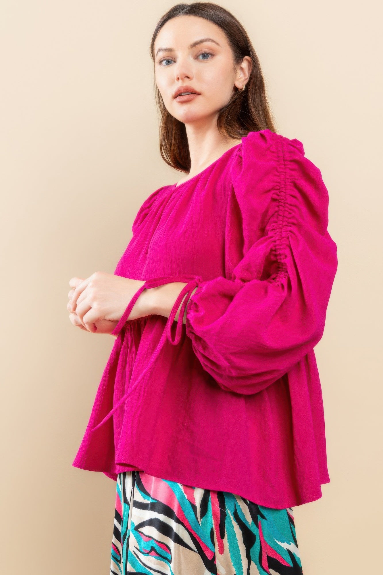 Magenta babydoll top side view with puff sleeves and drawstring ties at cuffs and hem flare
