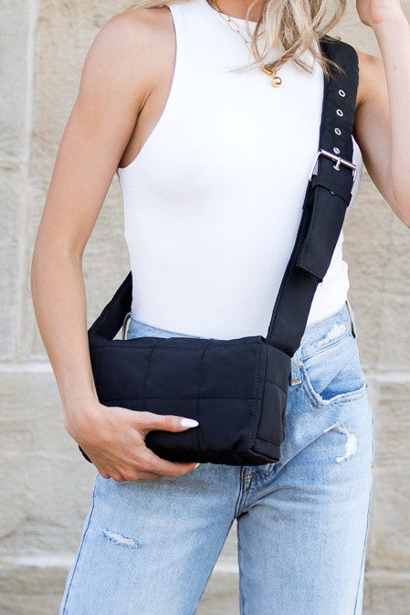 Black puffer crossbody bag with foldover flap and adjustable shoulder strap