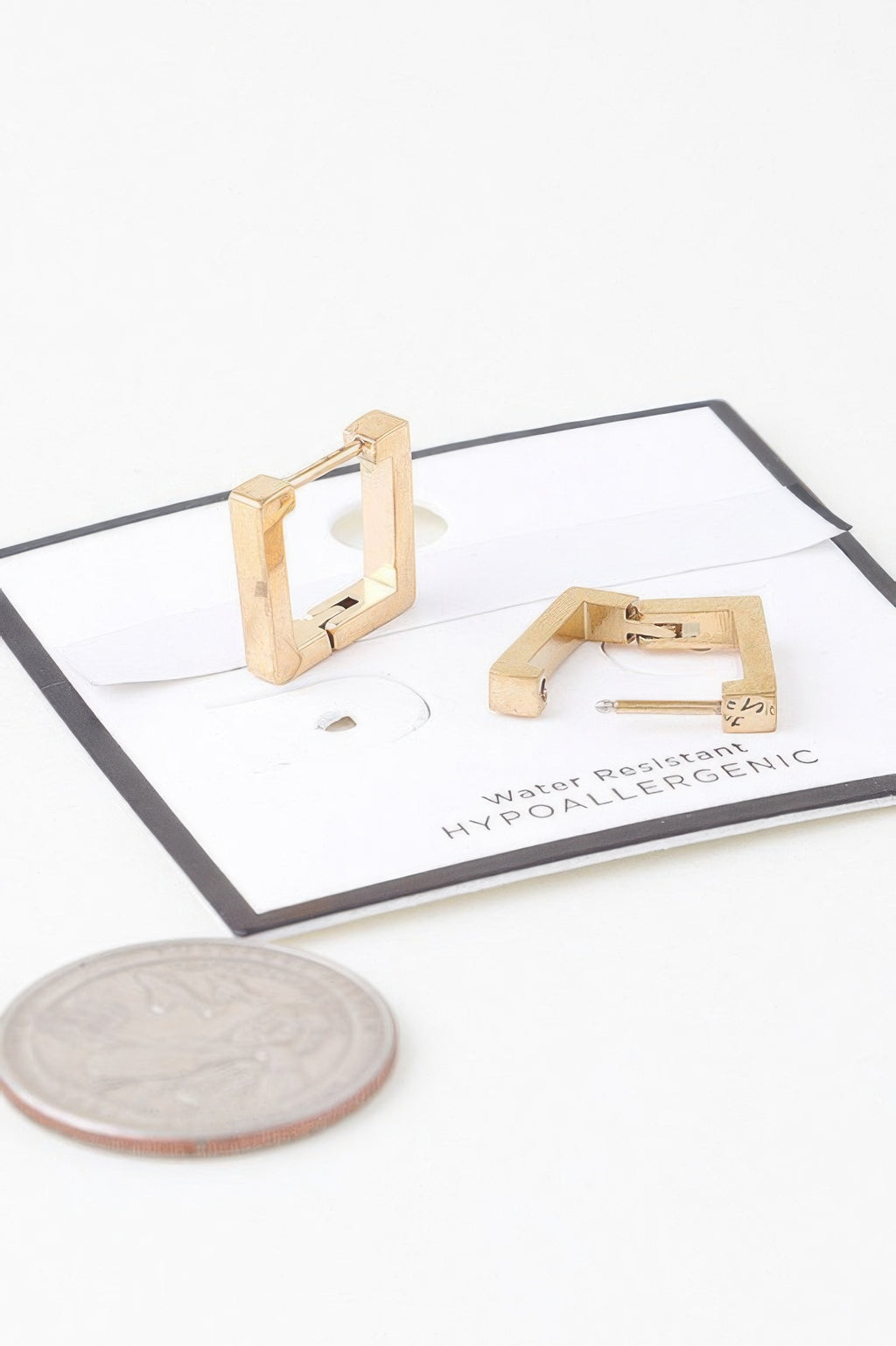 Gold cubic hoop earrings set on display with coin for scale