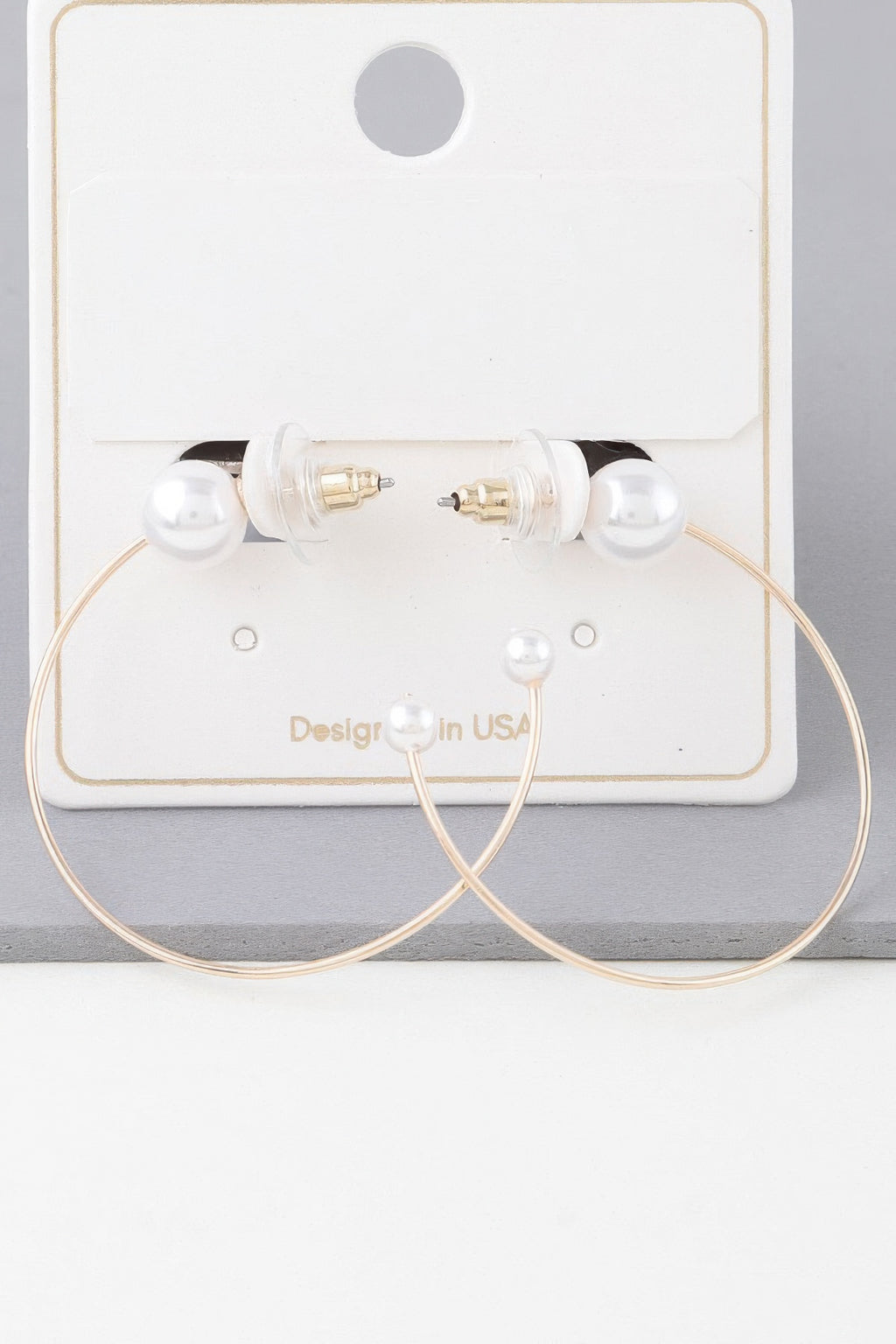 Pearl hoop earrings set on a display card; gold-toned hoops with white pearl tips