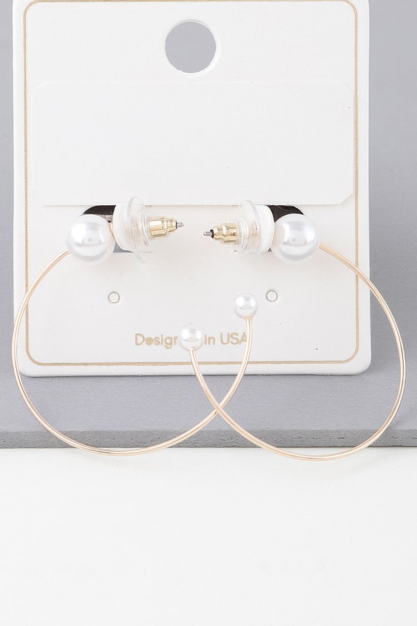 Pearl hoop earrings set on a display card; gold-toned hoops with white pearl tips