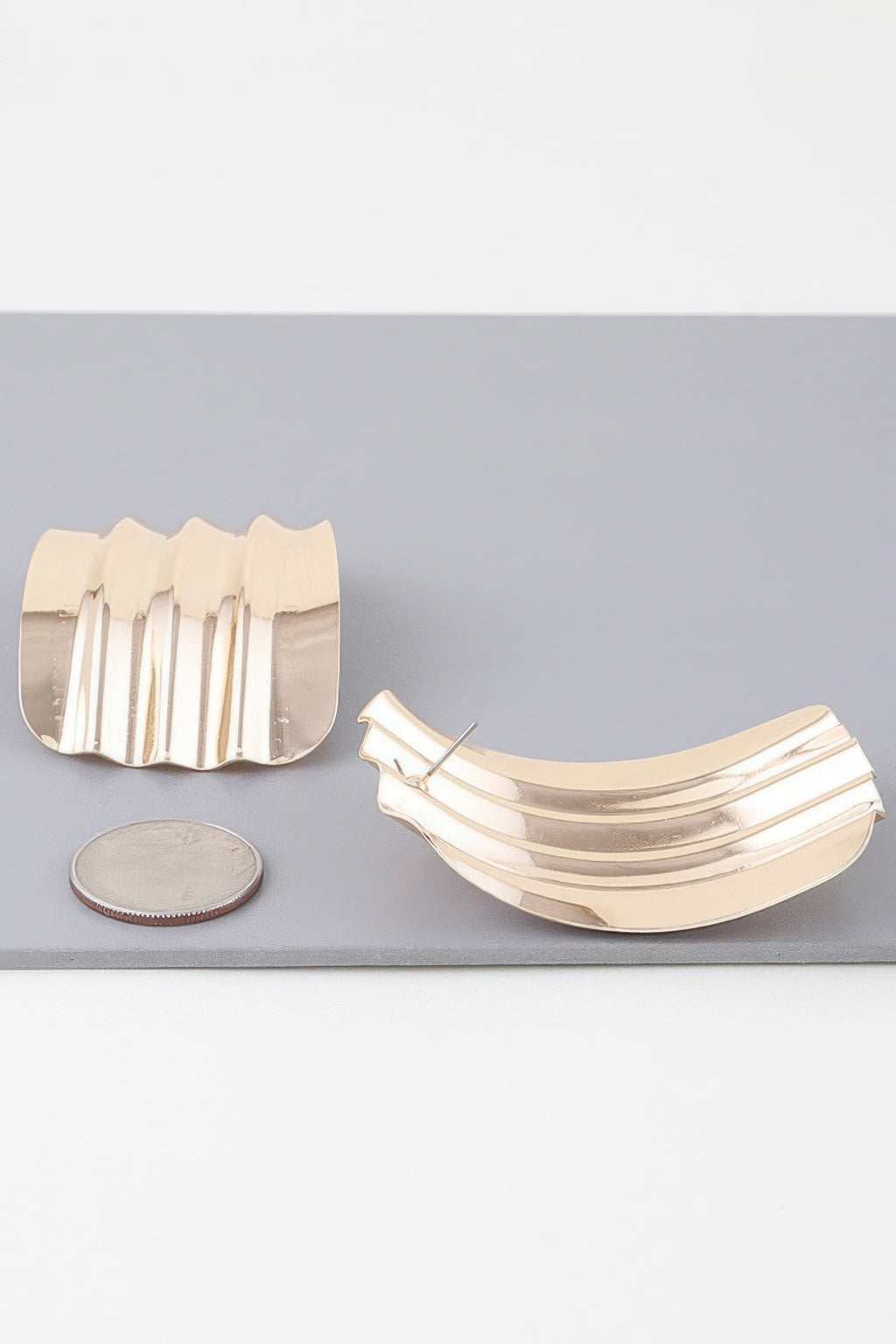 Gold ribbed curve earrings with visible posts; curved scalloped design with vertical ridges