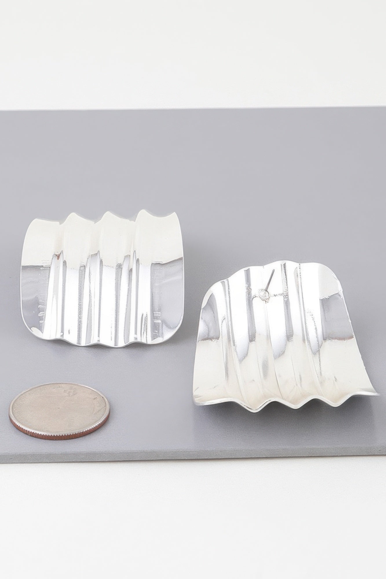 Shiny ribbed curve earrings in silver tone with post backs and scalloped wavy edge