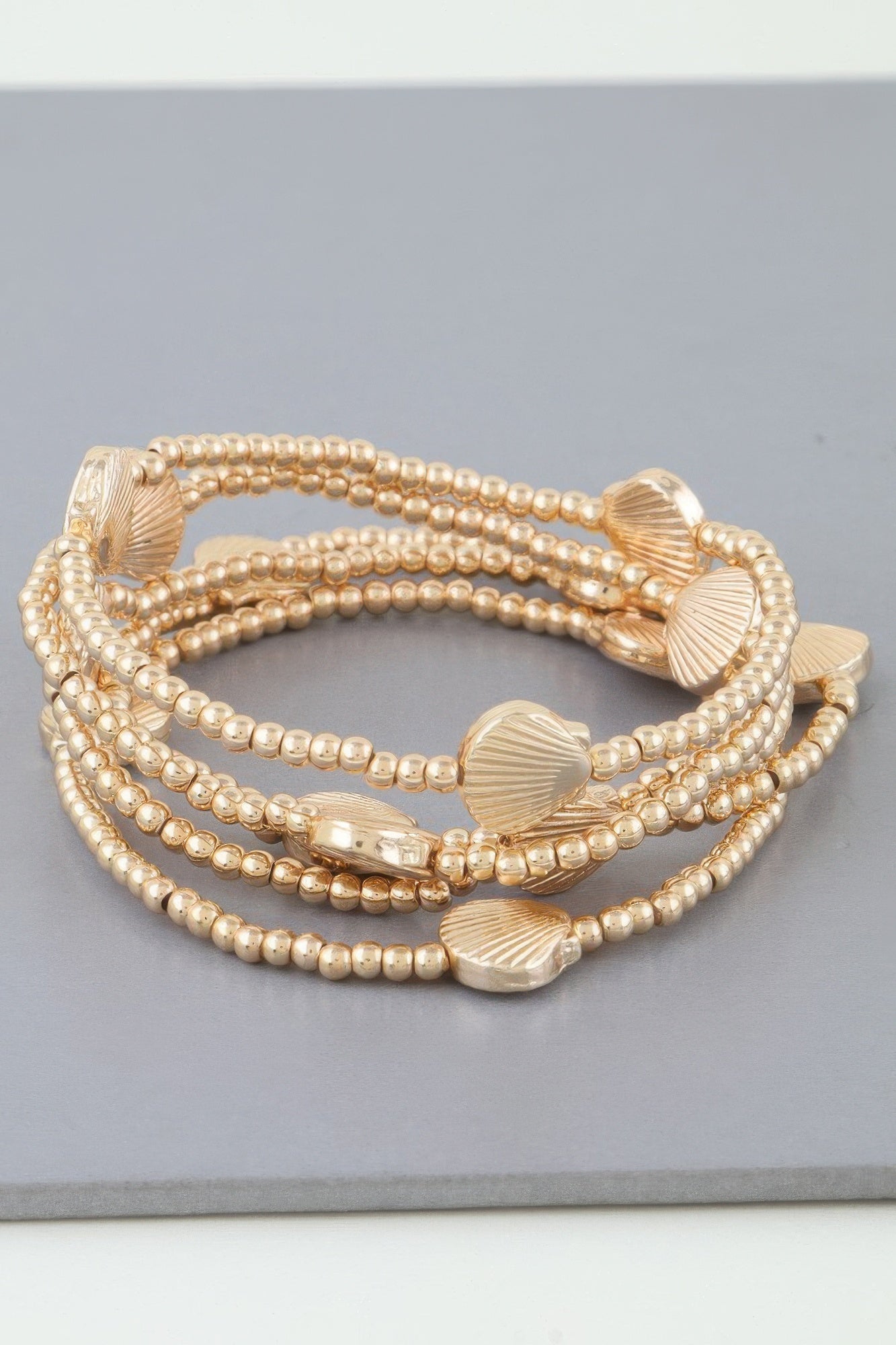 Gold-tone multi-strand bracelet with round beads and scallop shell accents