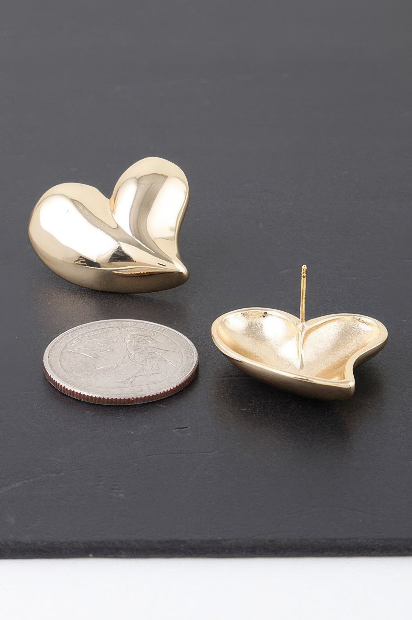 Gold heart stud earrings, glossy twin hearts with visible thin post and coin scale