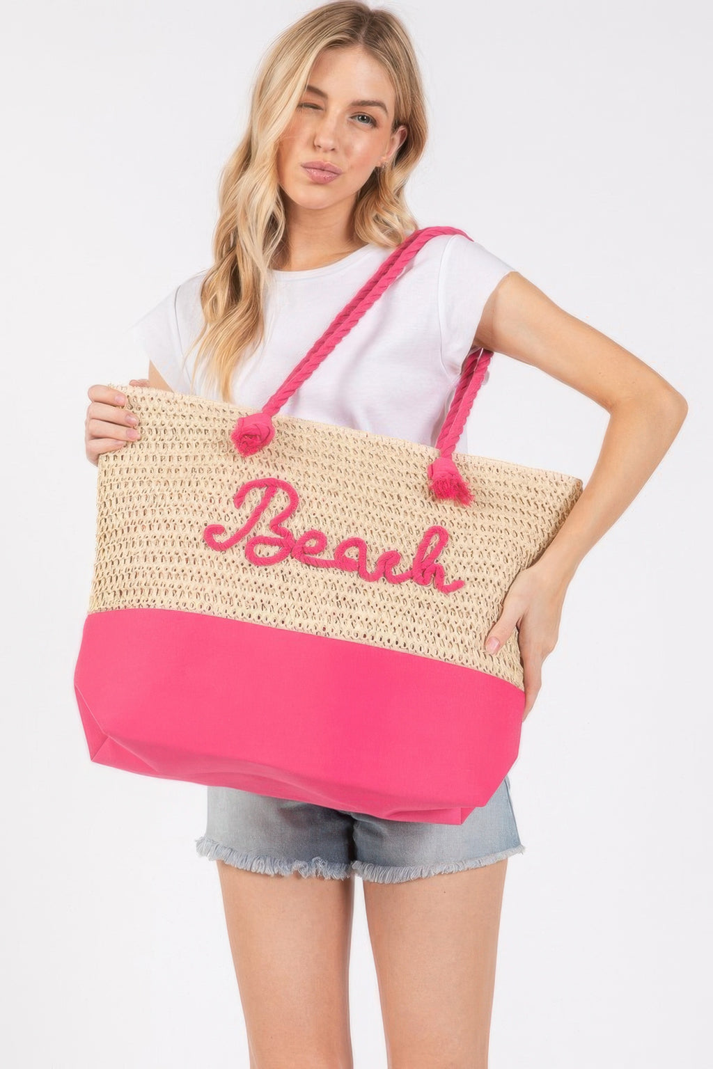 Crochet beach tote, beige knit with hot-pink bottom, rope straps and “Beach” lettering