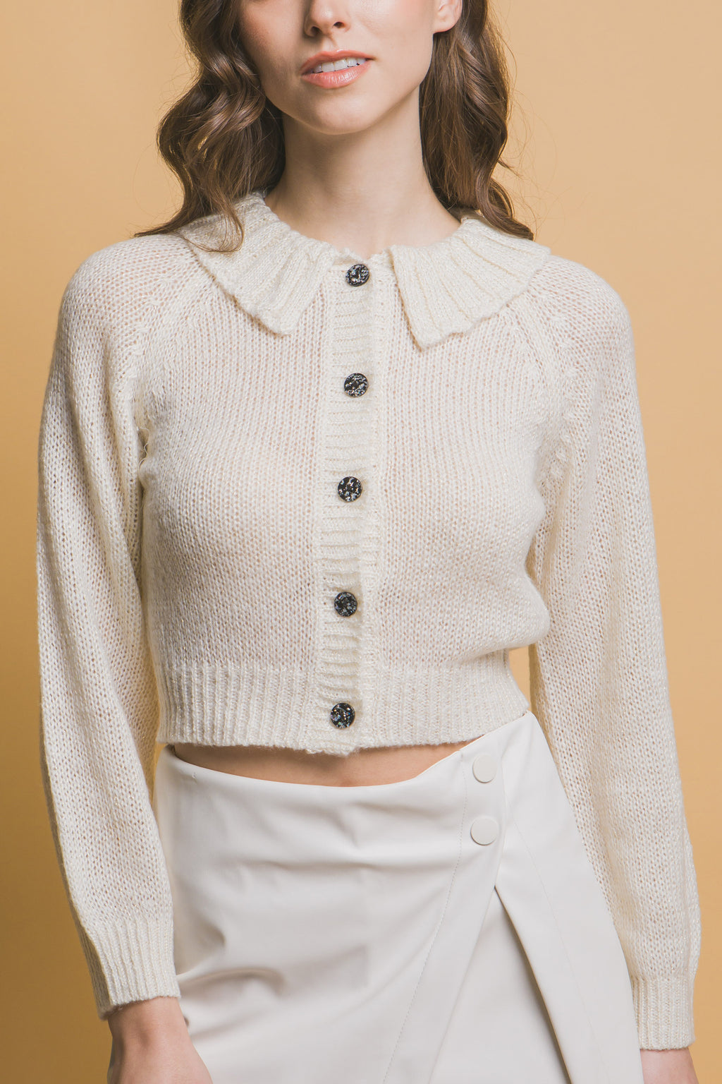 Off-white cropped collared sweater with black buttons and ribbed hem