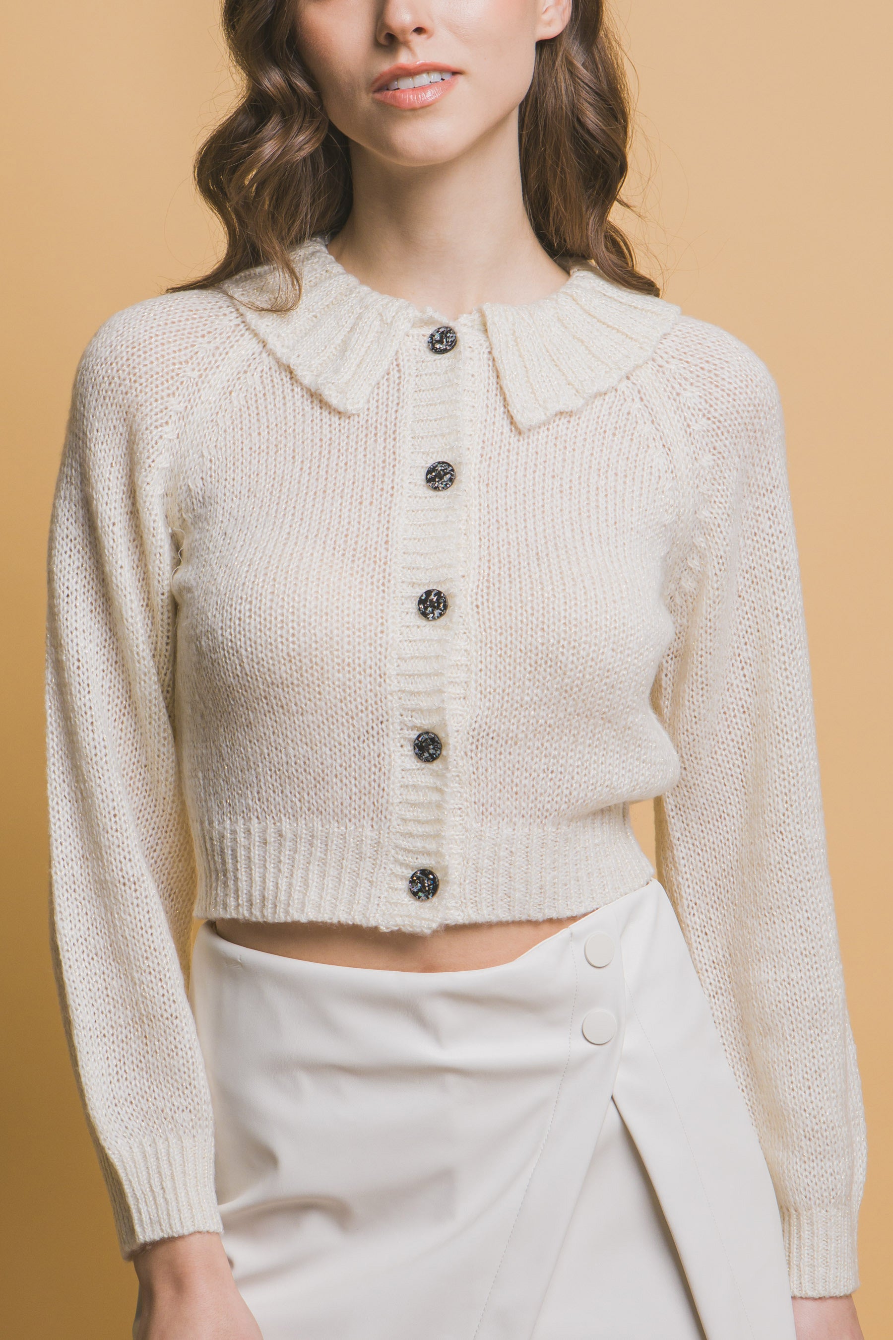 Off-white cropped collared sweater with black buttons and ribbed hem