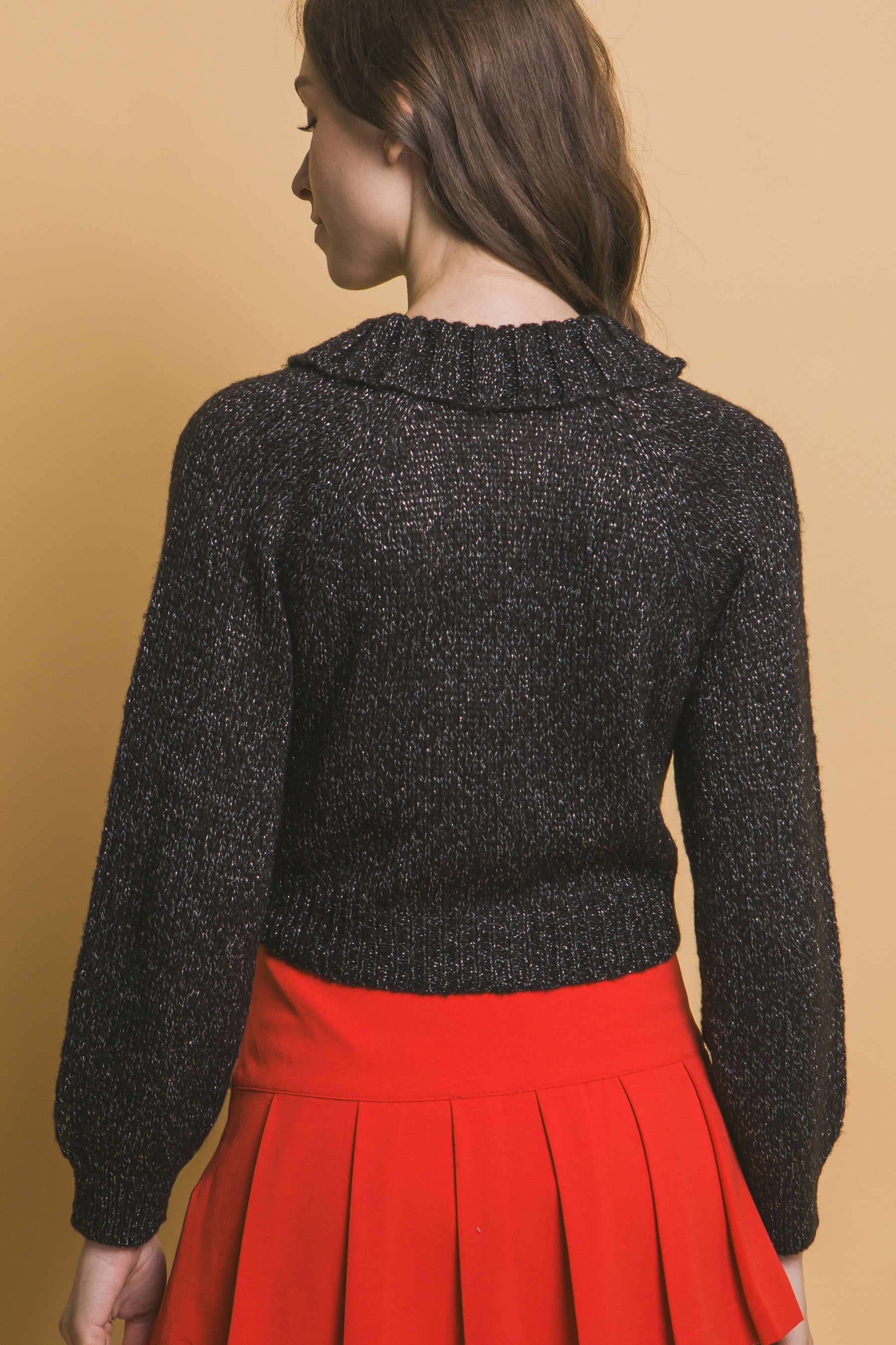Back view of black cropped knit sweater with high collar and ribbed cuffs