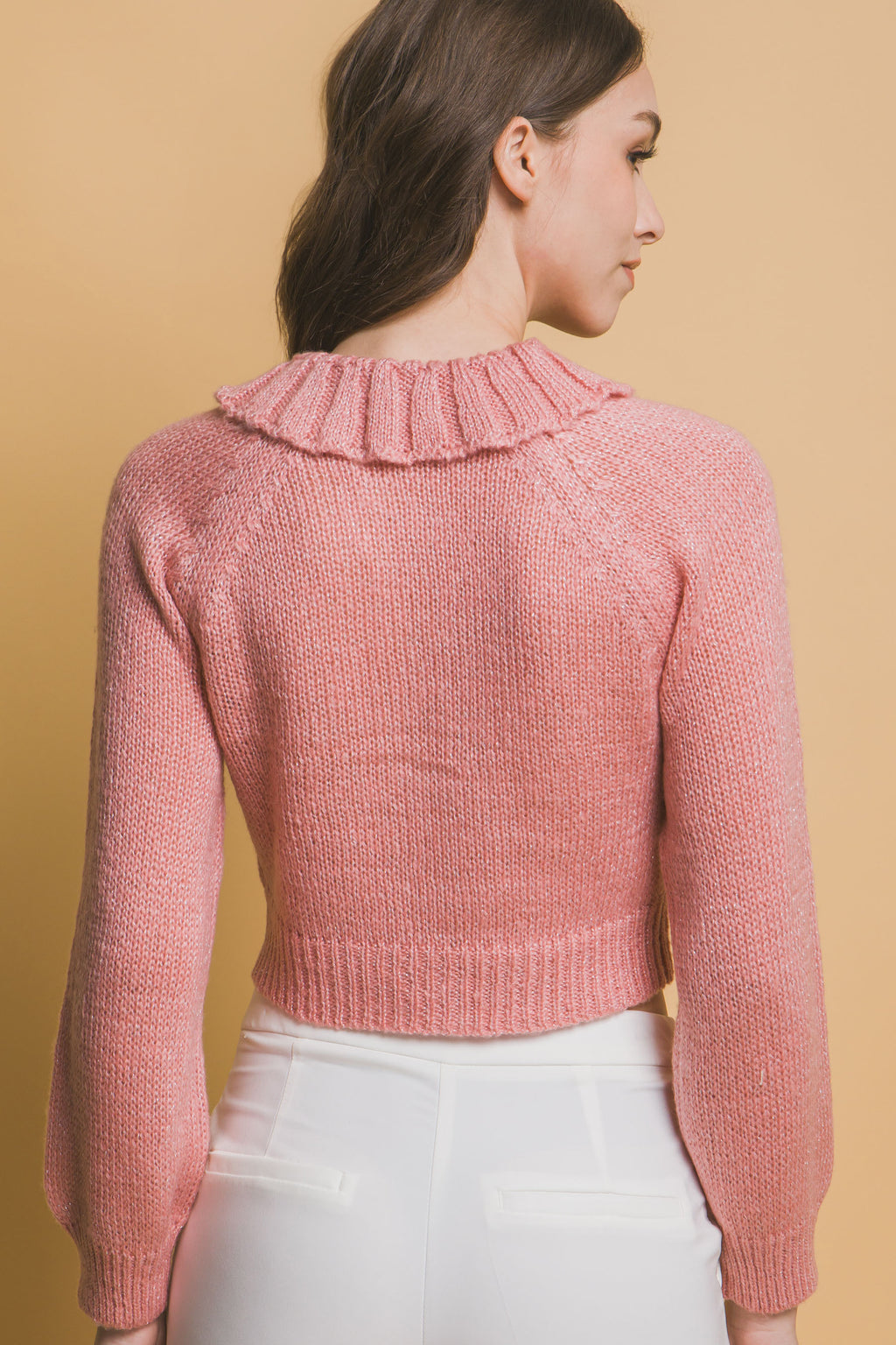 Back view of pink cropped knit sweater with high ribbed collar and sleeves
