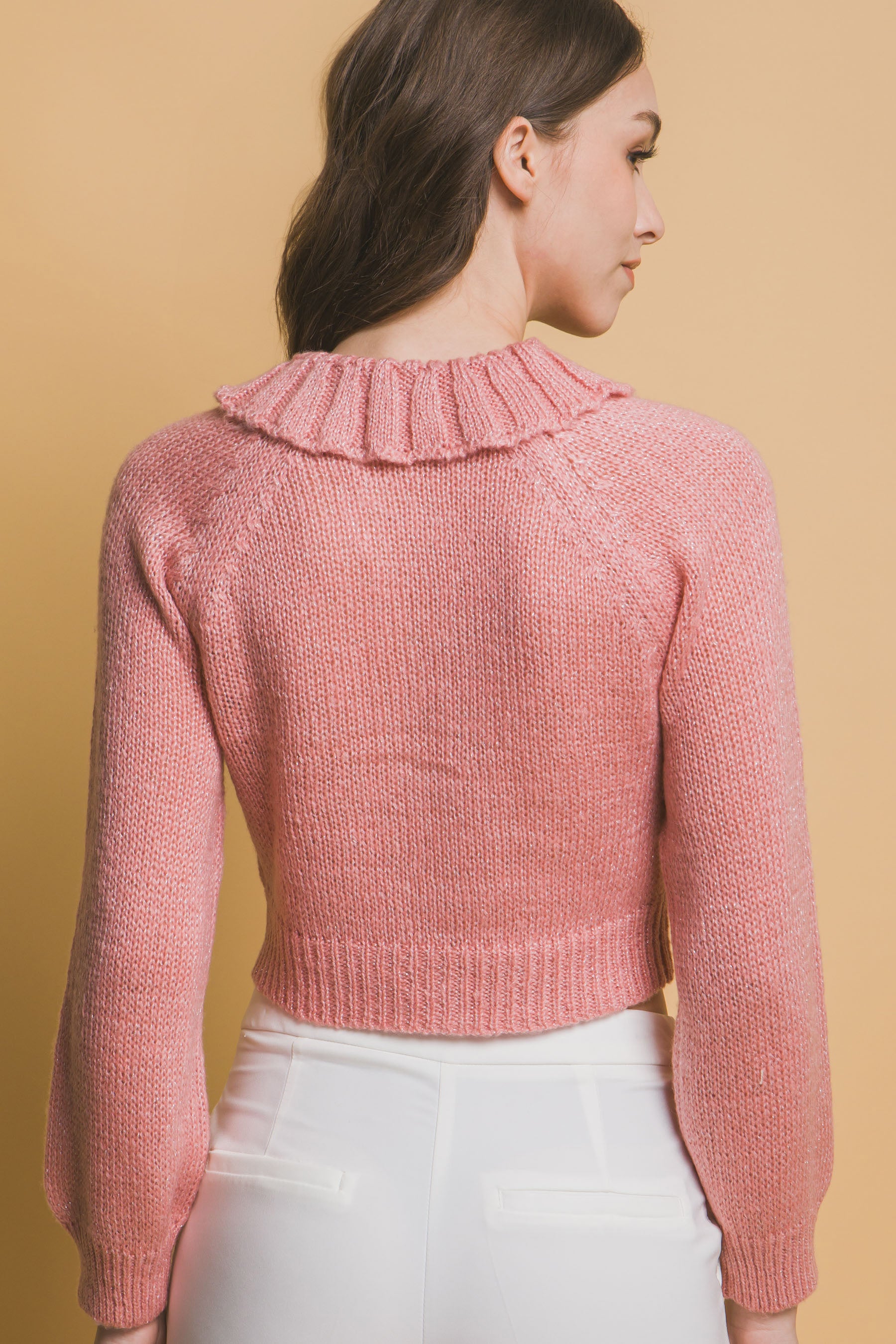 Back view of pink cropped knit sweater with high ribbed collar and sleeves