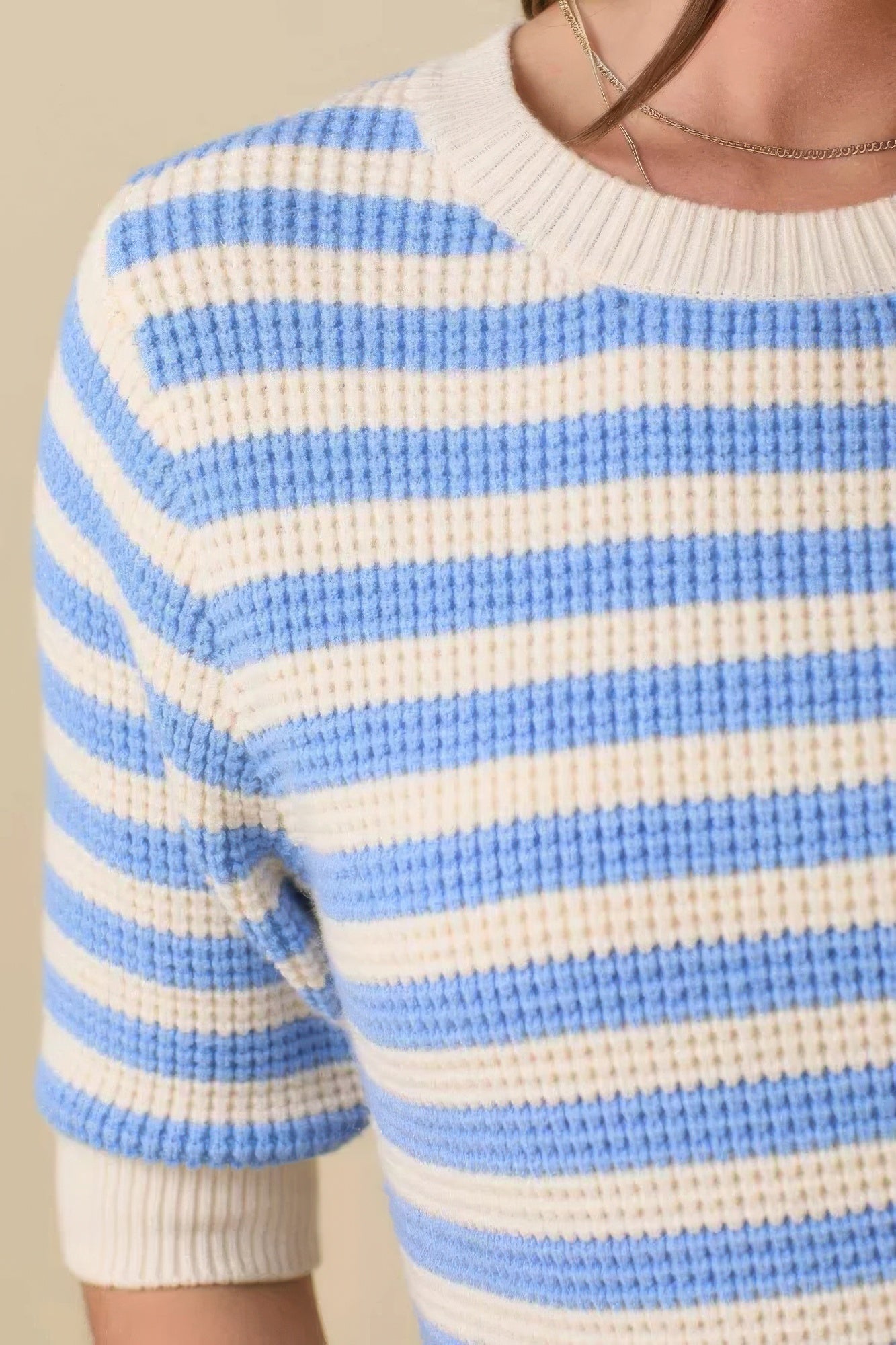 Close-up: cream-and-blue striped knit sweater sleeve with ribbed cuff