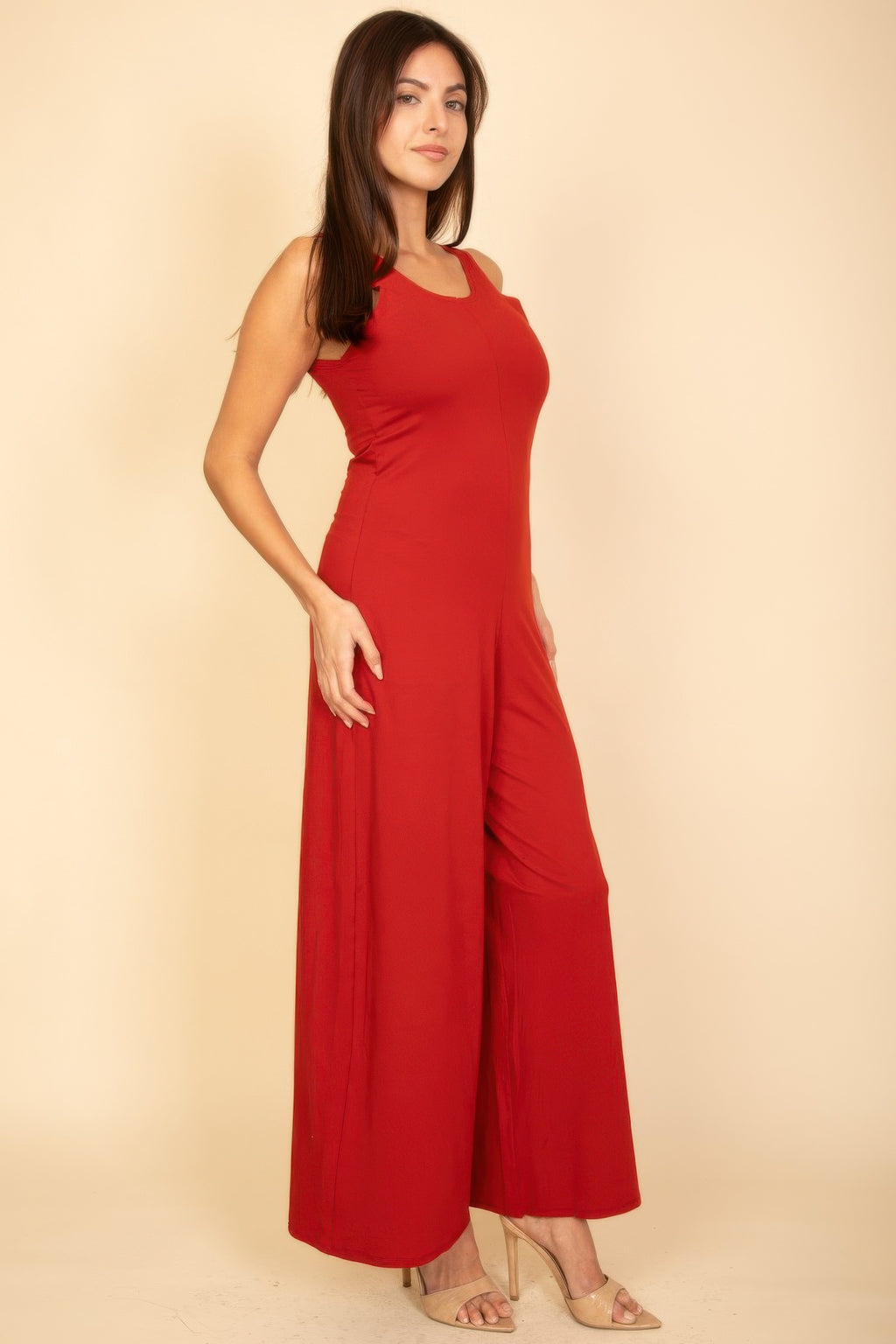 Red sleeveless jumpsuit, front three-quarter view with draped wide-leg silhouette