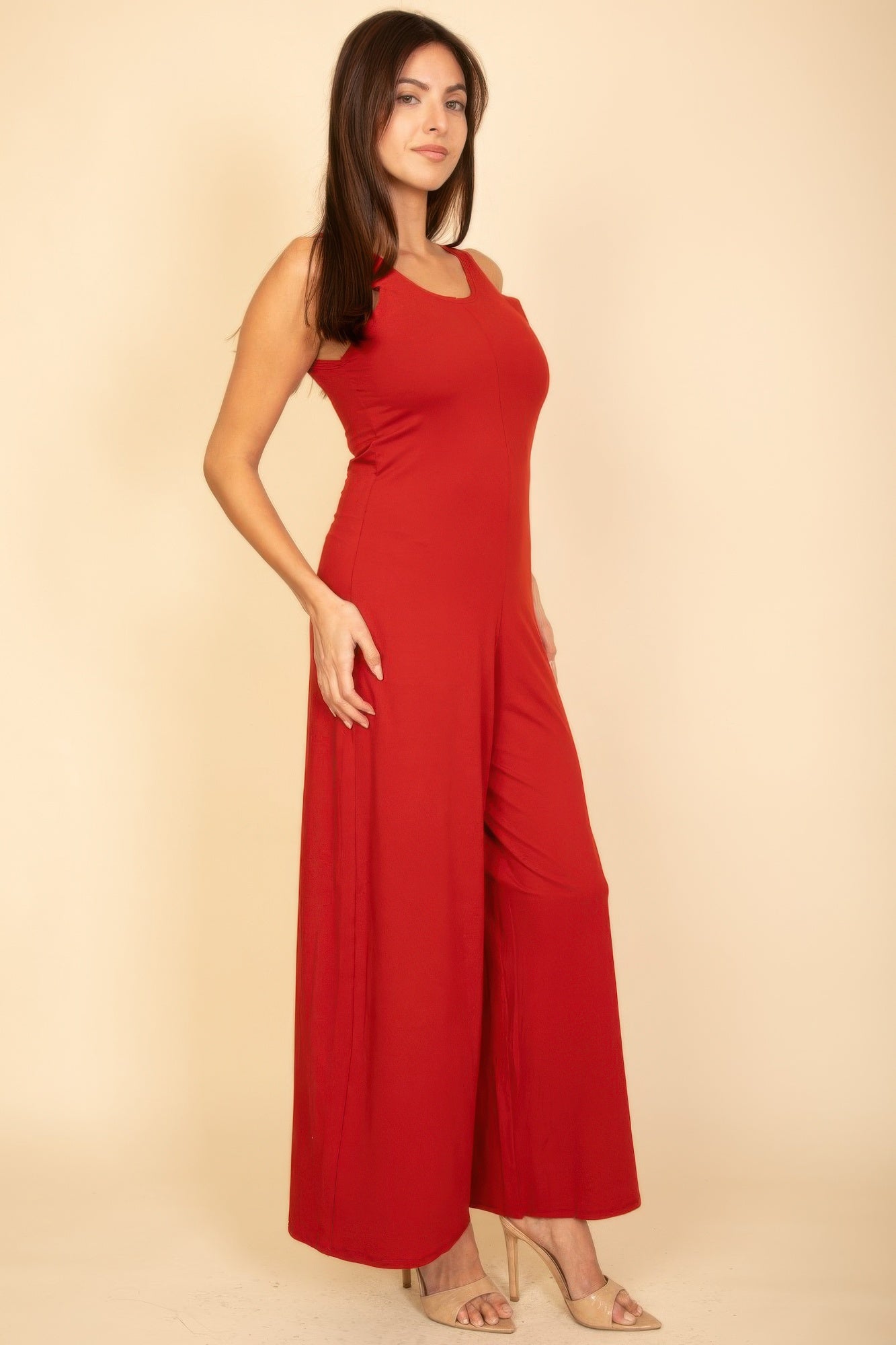 Red sleeveless jumpsuit, front three-quarter view with draped wide-leg silhouette