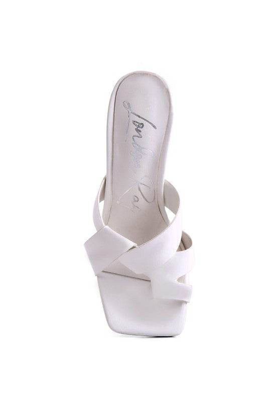 White heeled sandals showing toe ring strap crossing over the foot