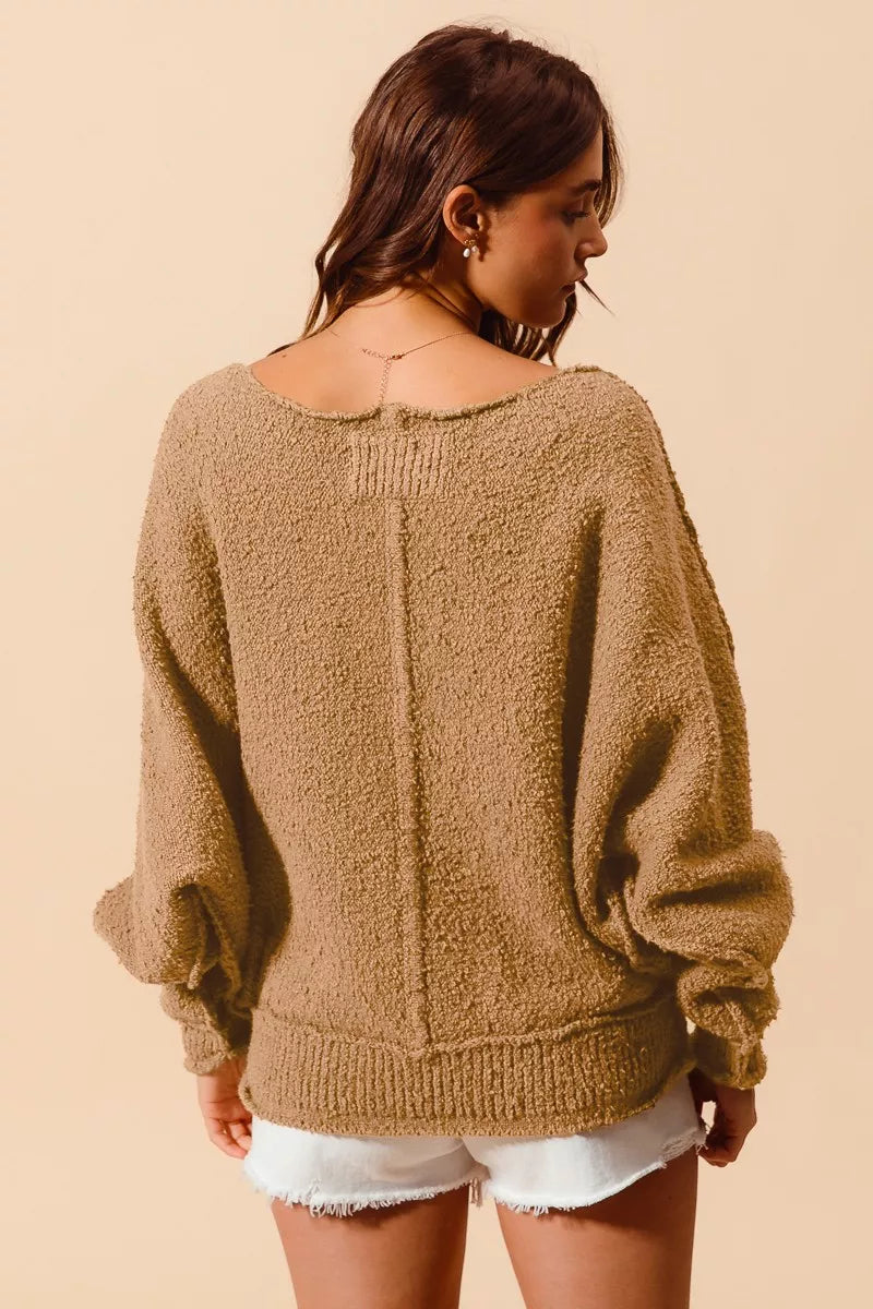 Back view: taupe boucle slouchy sweater with exposed center seam and loose cuffs