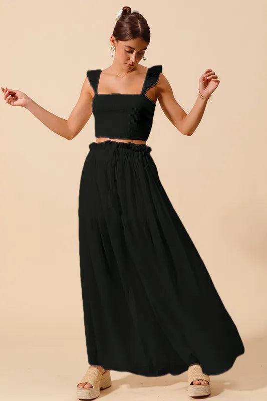 Black smocked crop top with square neckline and pleated maxi skirt, front