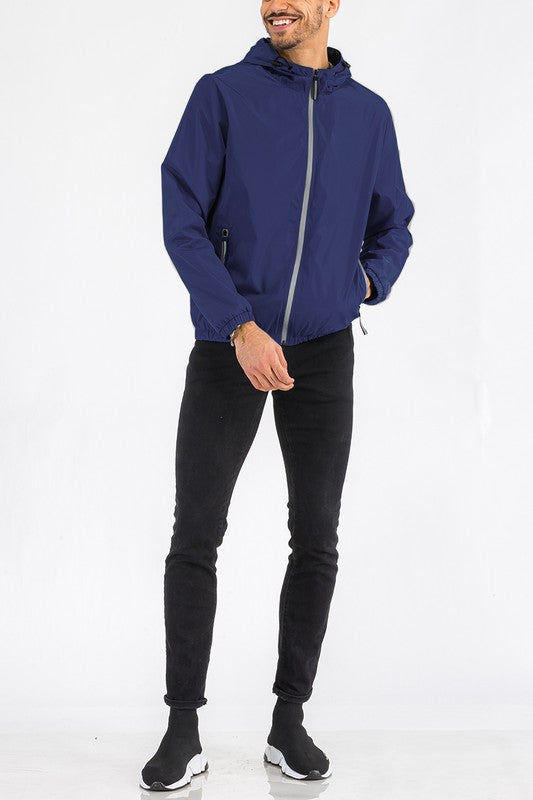 Navy lightweight windbreaker jacket on model, full-zip with hood and elastic cuffs.