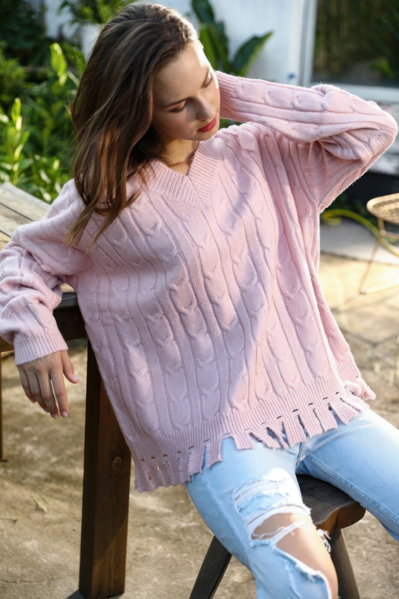 Light pink cable-knit sweater, crew neck, long sleeves, frayed ripped hem detail