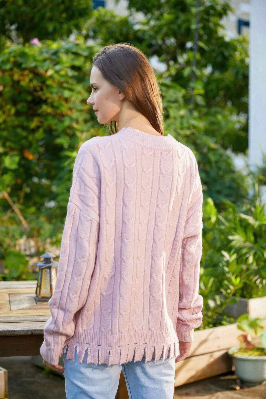 Back of light pink cable-knit sweater, crew neck, long sleeves, ribbed hem