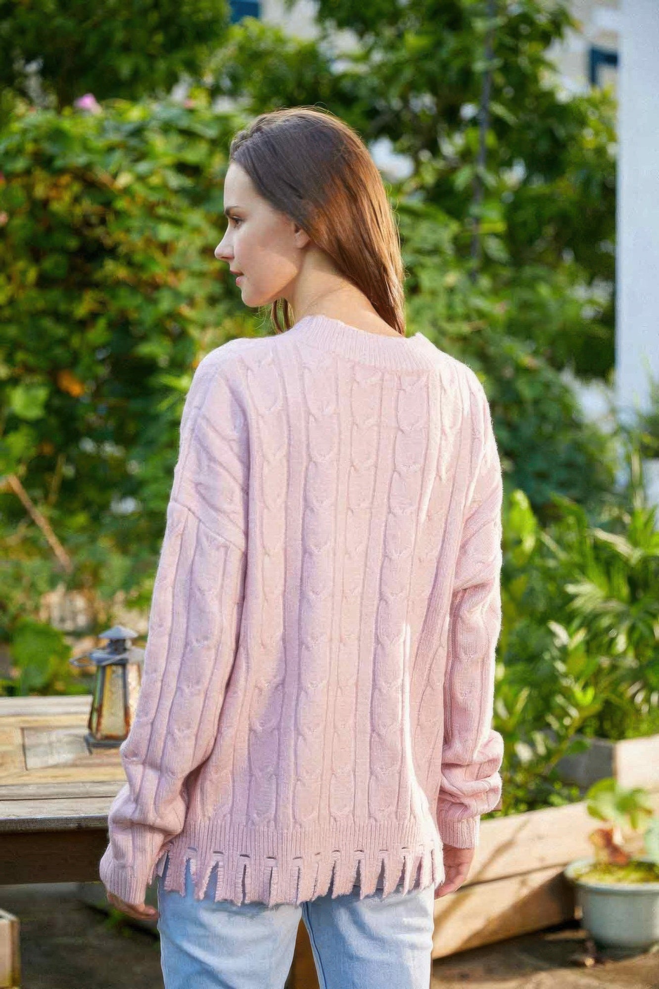 Back of light pink cable-knit sweater, crew neck, long sleeves, ribbed hem