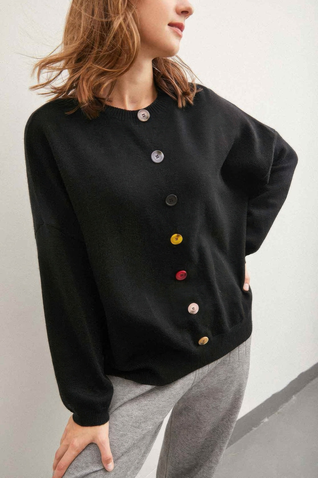 Black knit sweater with colorful round buttons on center placket and crew neck