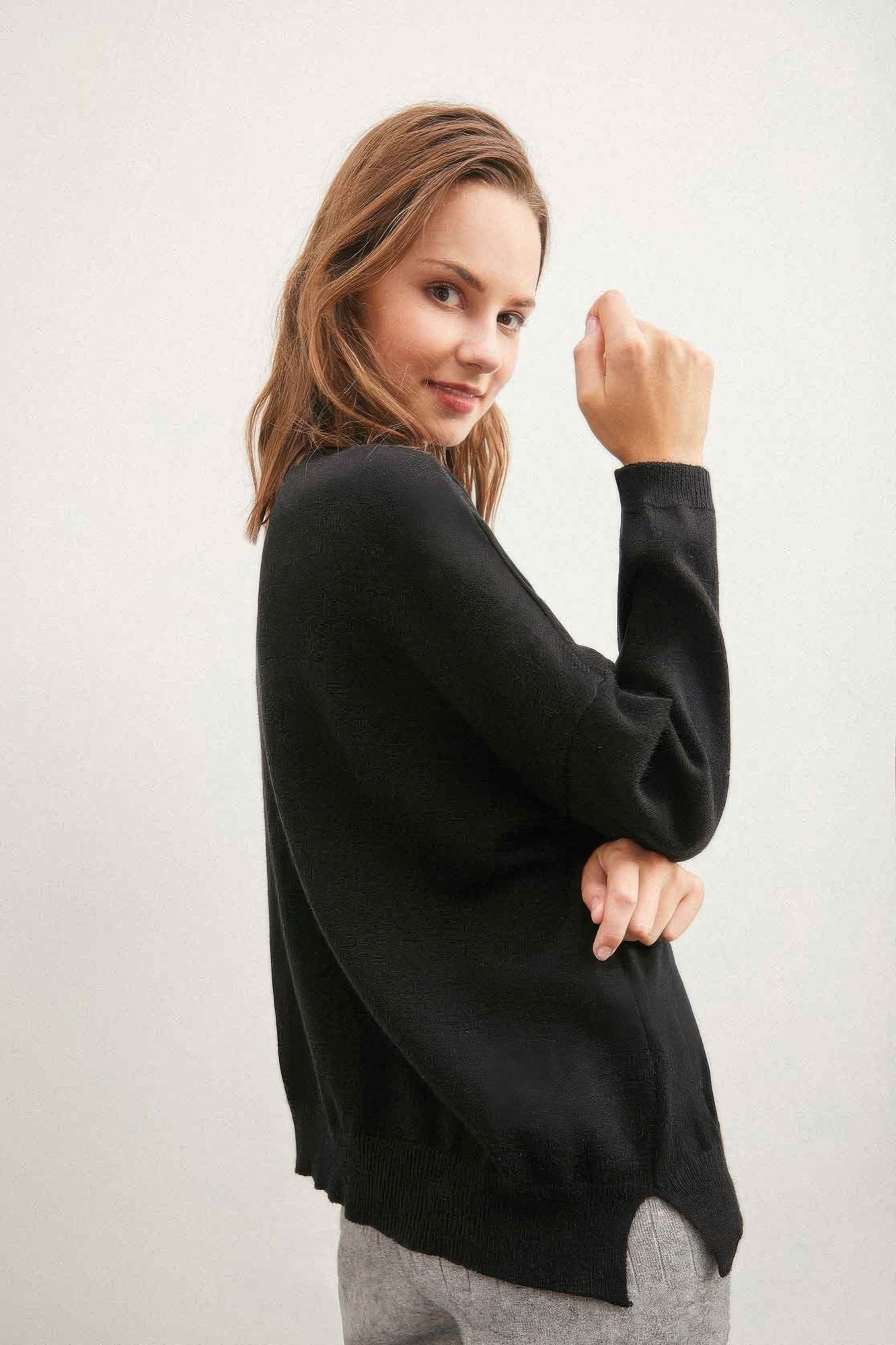 Black solid sweater with colorful buttons, side view with curved hem
