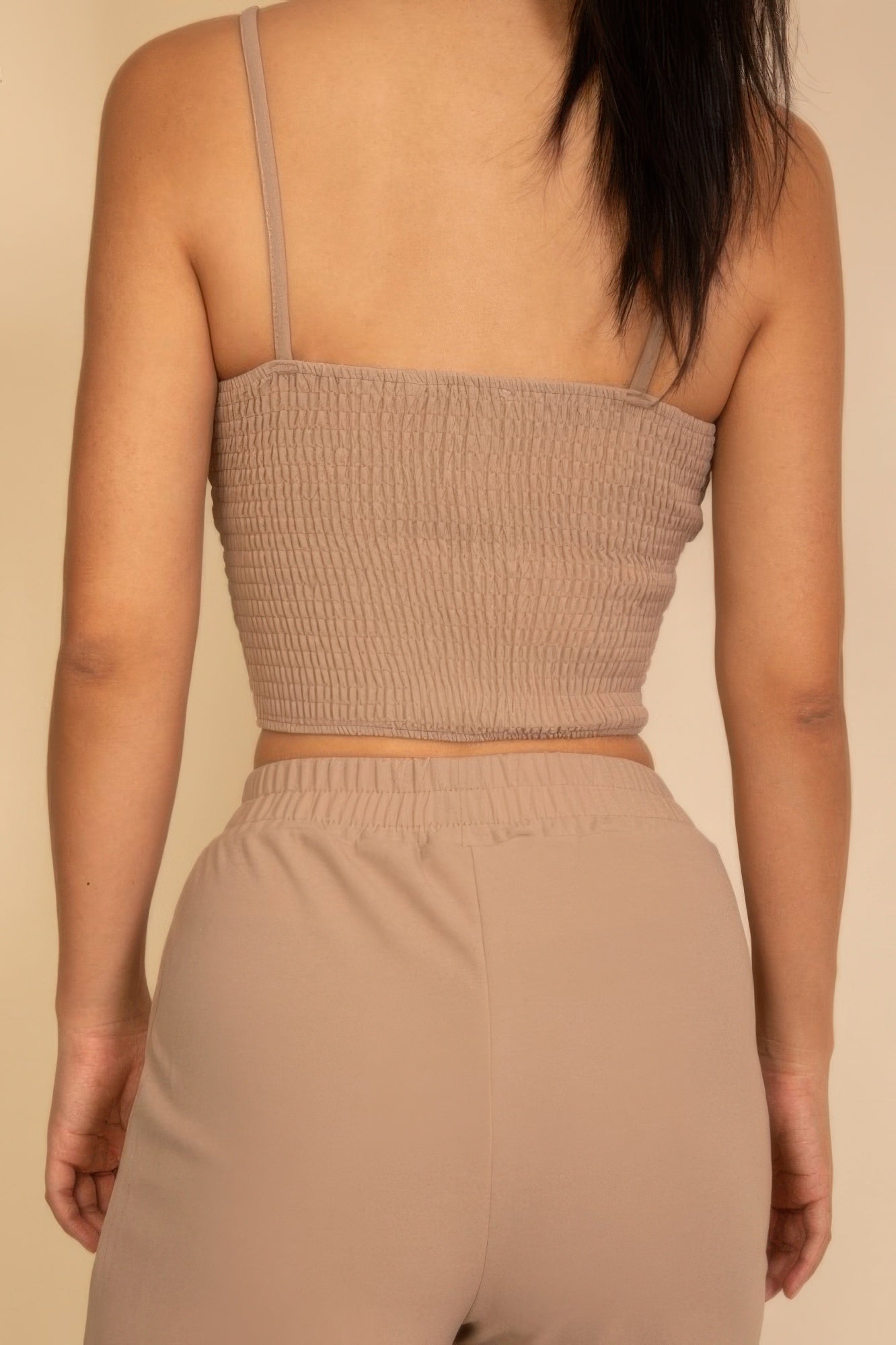 Close-up back view: textured spaghetti strap bralette and wide-leg pants, taupe