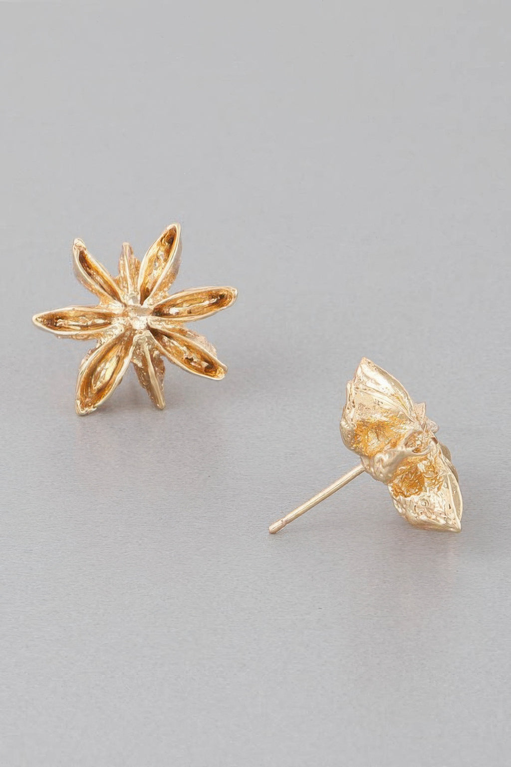 Gold spice flower stud earrings; one earring shows the straight post behind petals