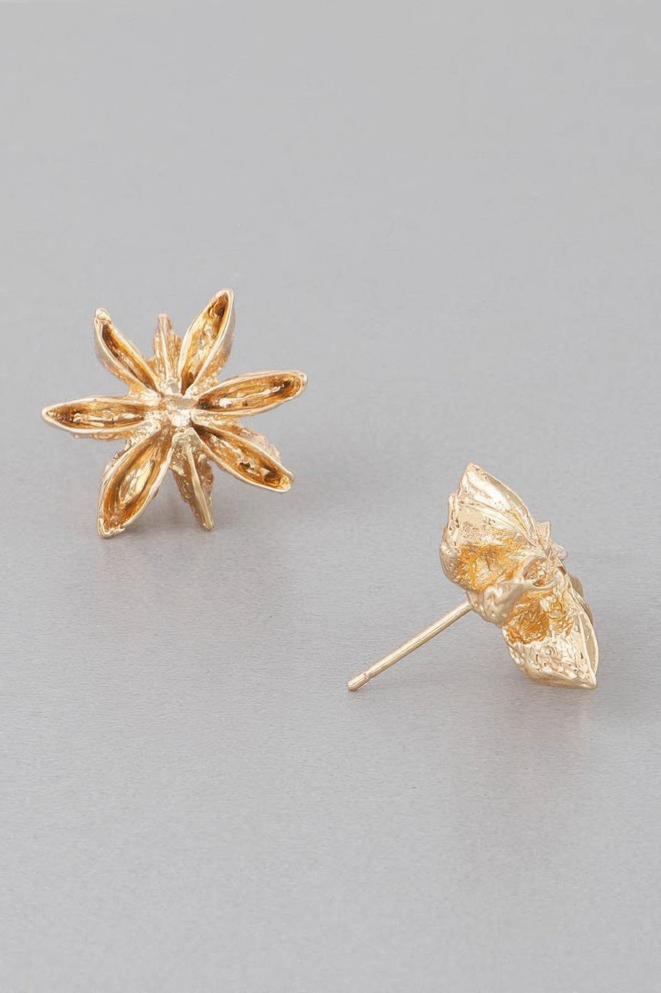 Gold spice flower stud earrings; one earring shows the straight post behind petals