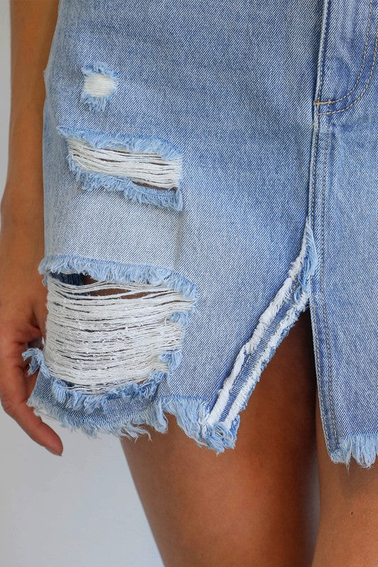 Light wash denim skirt close-up with large ripped panels and frayed raw edges