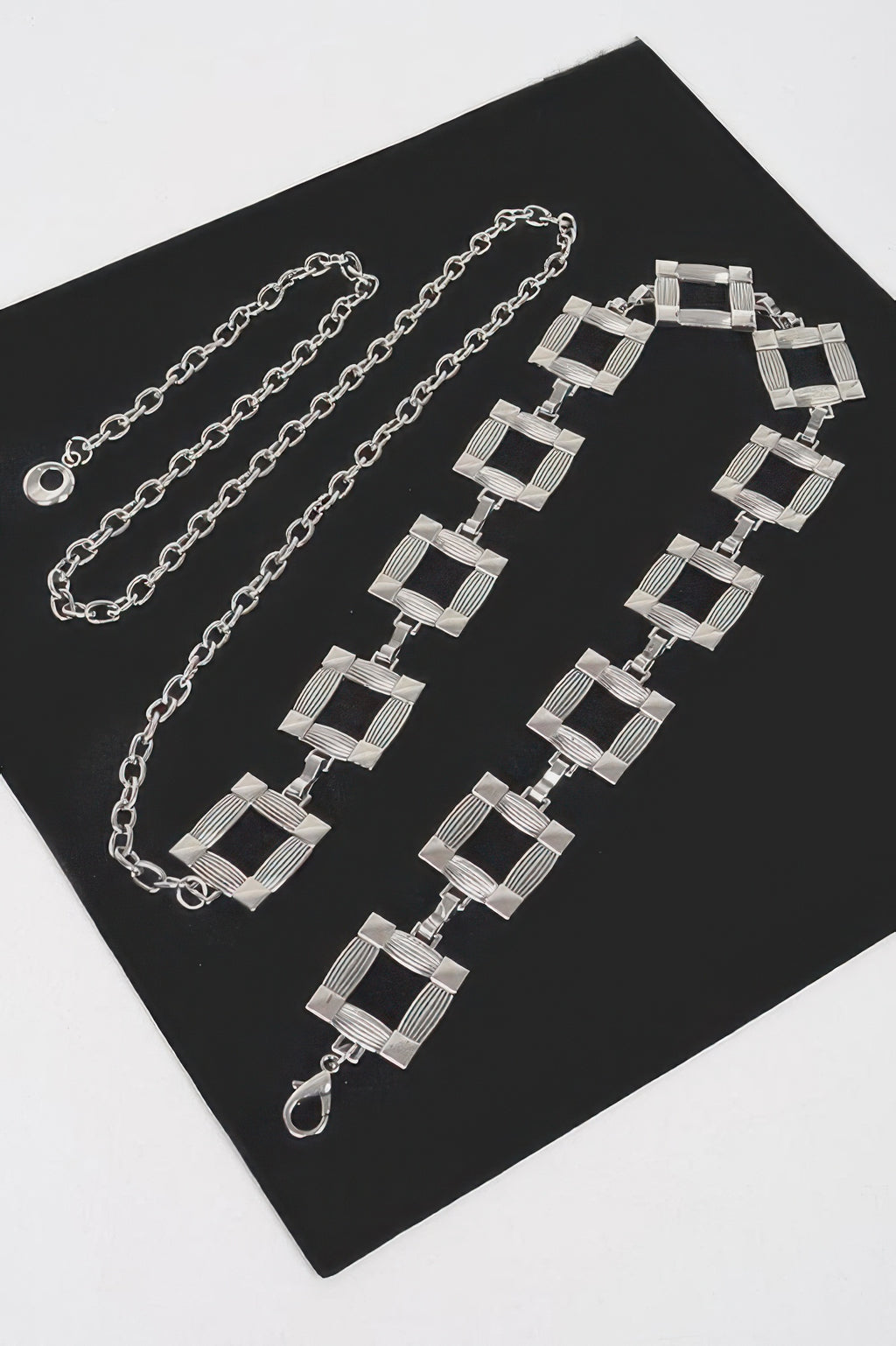 Square metal chain belt with interlinked square blocks and clasp, silver tone.