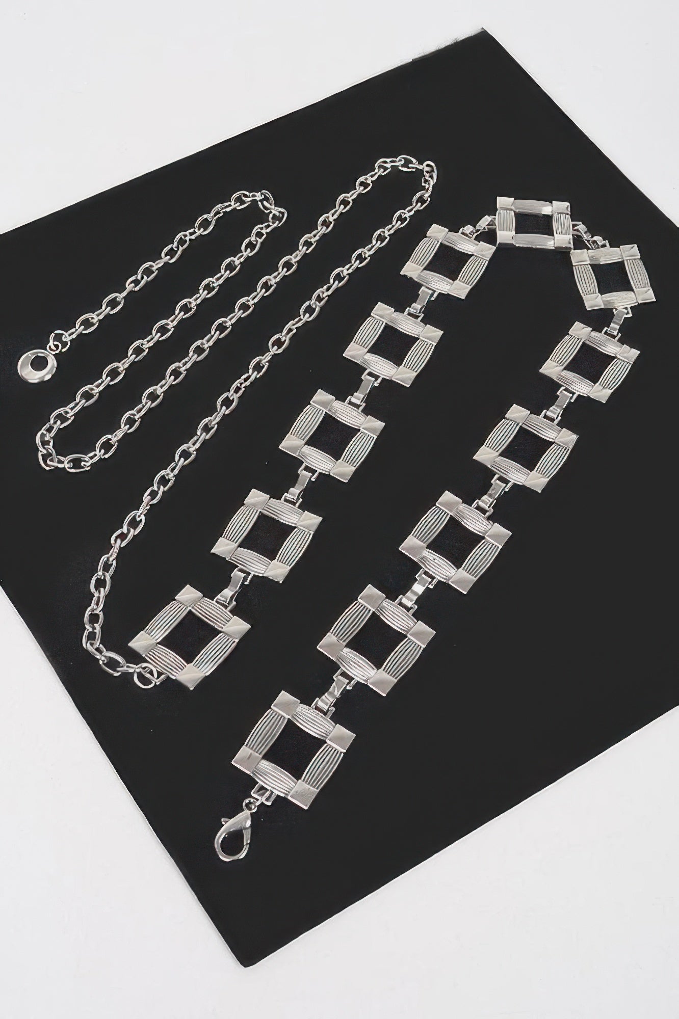Square metal chain belt with interlinked square blocks and clasp, silver tone.