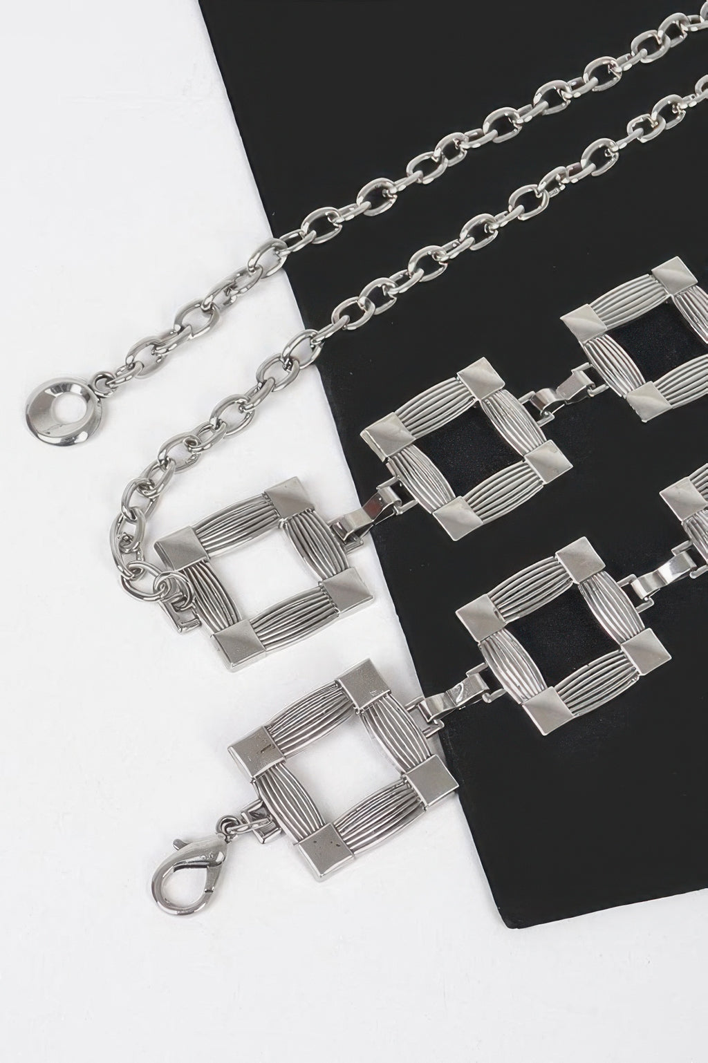 Close-up of silver square metal chain belt links and round clasp ring.