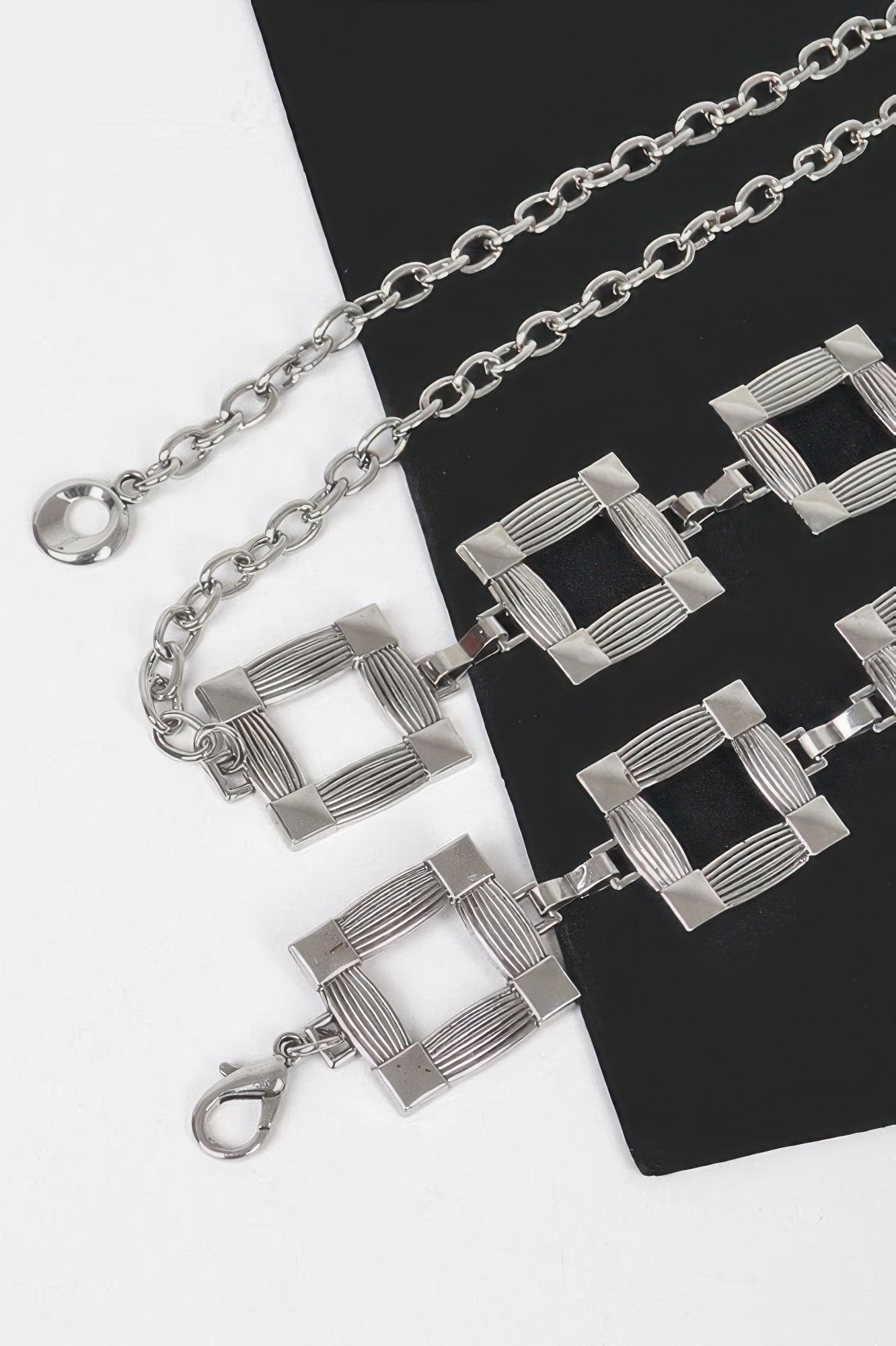 Close-up of silver square metal chain belt links and round clasp ring.