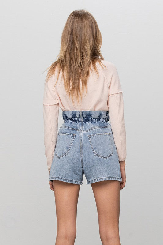 Back view of light-wash denim shorts with high-rise elastic waistband and patch pockets