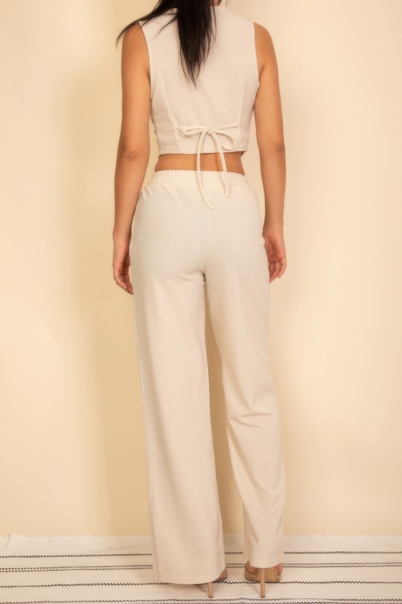 Off-white wide-leg pants with tie-front waist and matching sleeveless button vest