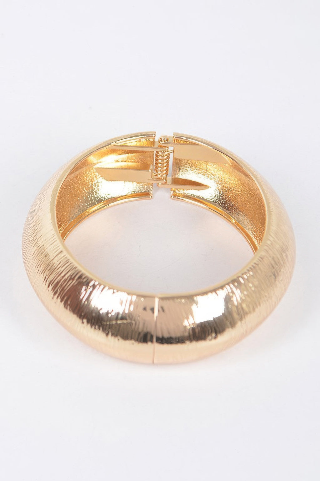 Gold textured metal bangle bracelet with clasp visible at the top center