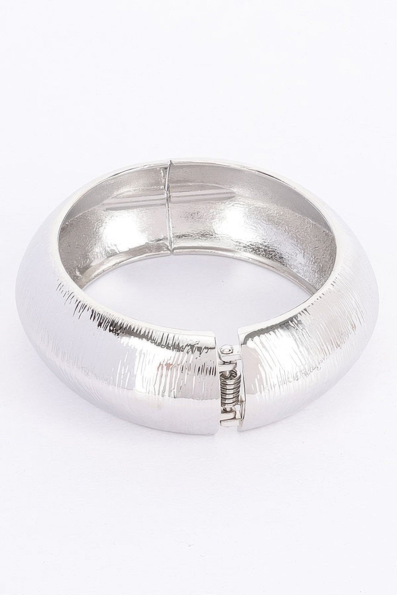 Silver textured metal bangle bracelet with hinge clasp and spring detail visible
