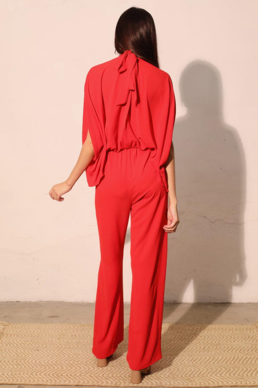 Back view of red caftan jumpsuit with bow-tie neck and wide-leg silhouette