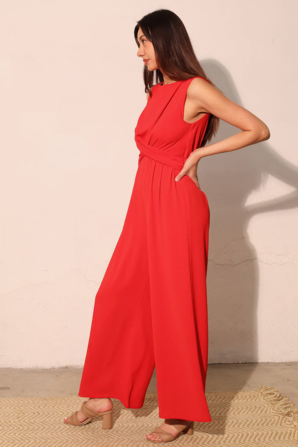 True red twist-front jumpsuit, side view with gathered waist and wide legs