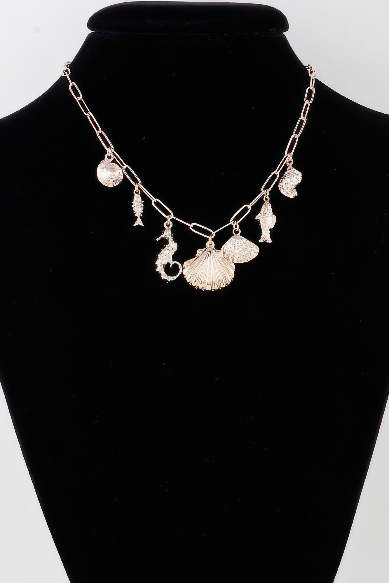 Gold sea-charm necklace with linked chain and shell, starfish, and fin pendants