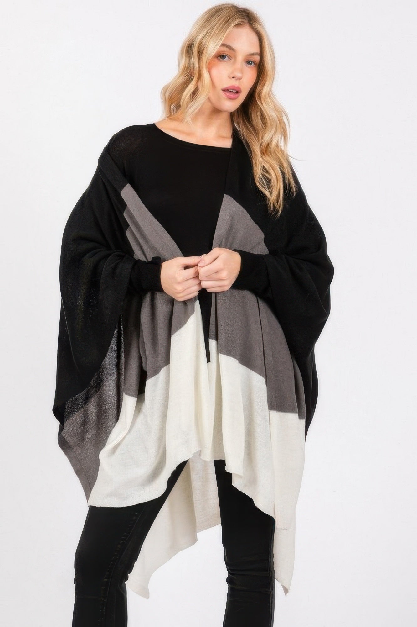 Three-tone ruana in black with gray and off-white blocks; wide draped silhouette.