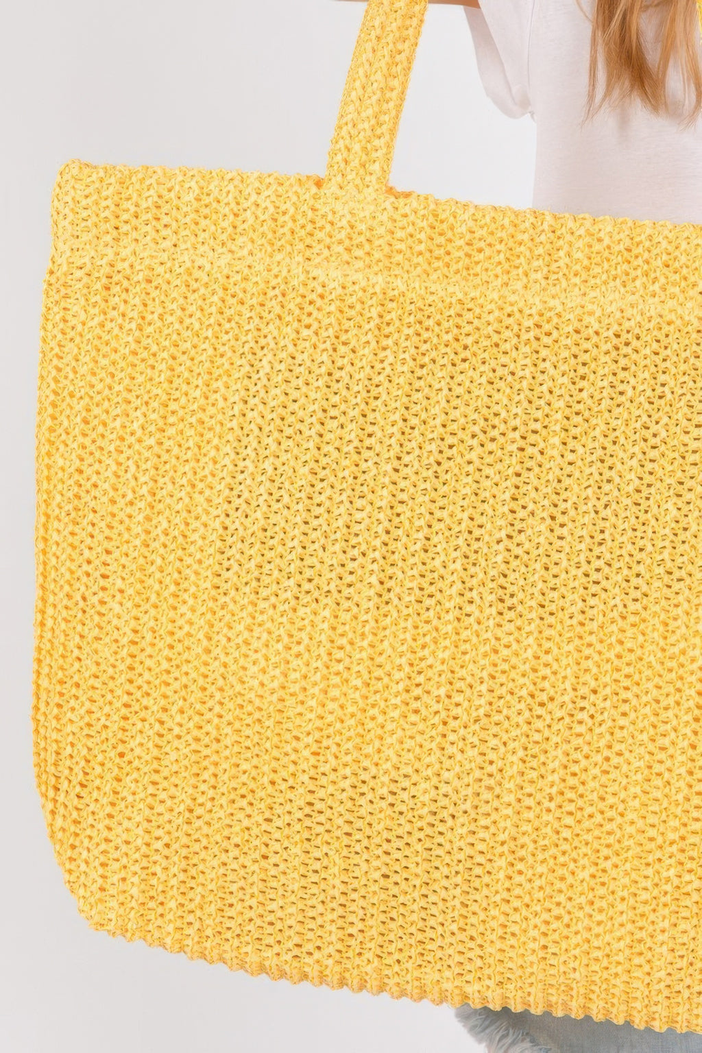 Close-up of yellow crochet straw tote bag with long handle