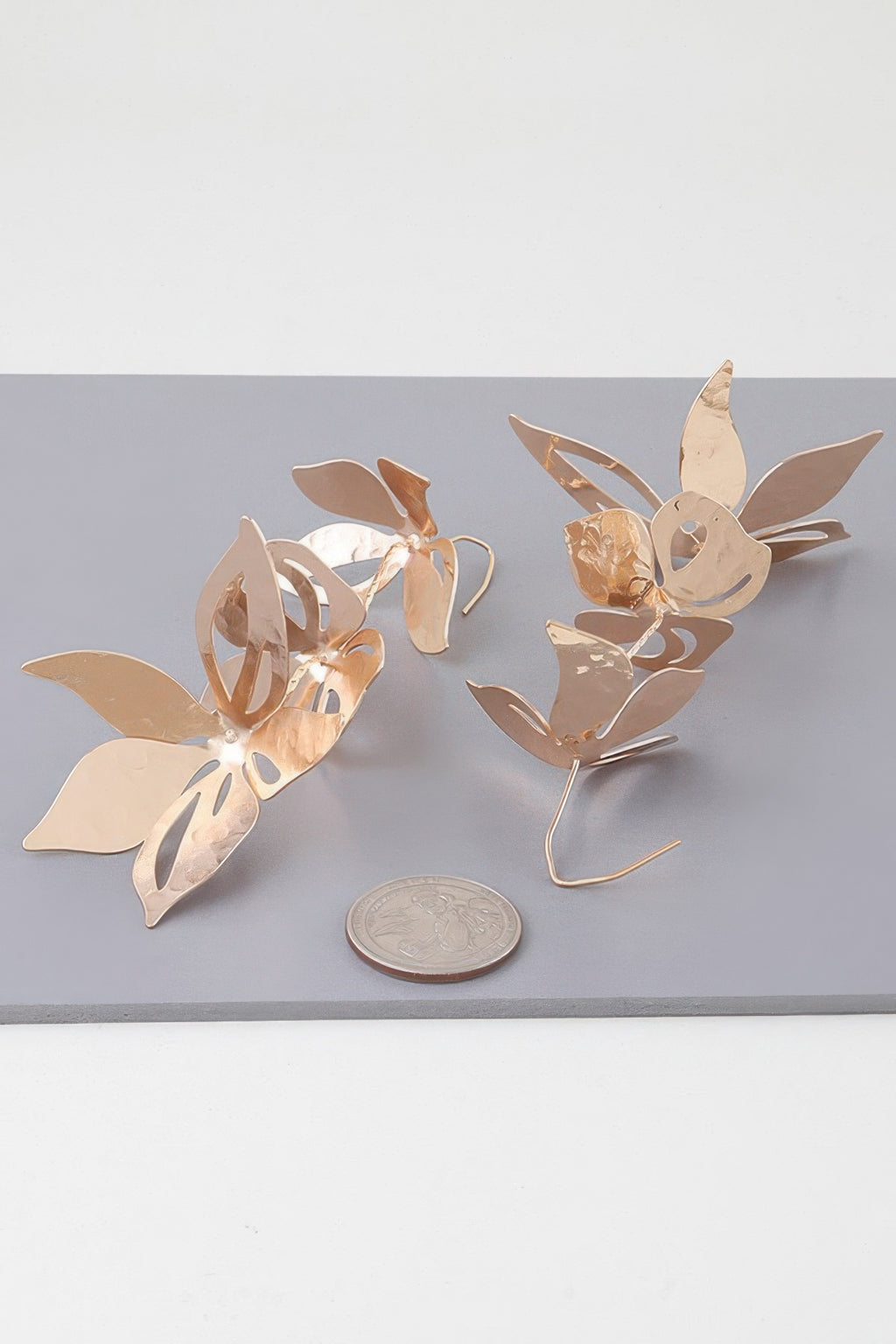 Gold triple flower drop earrings, fan-shaped petals; shown with coin for size